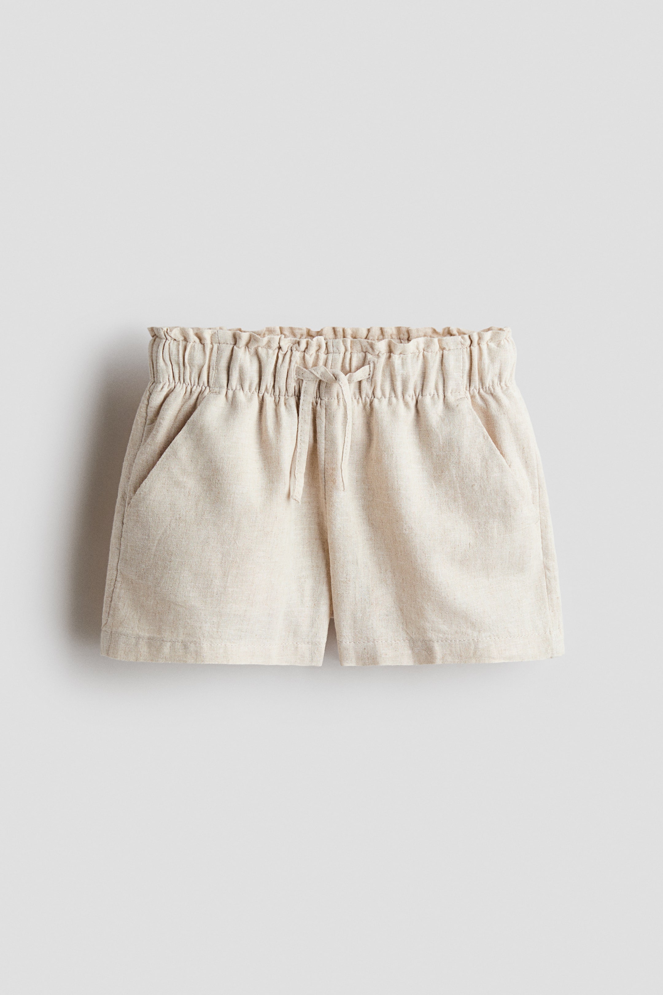 View larger image: Loose-fit shorts crafted from a breathable linen-cotton blend are showcased from the front. They boast diagonal side pockets and an elasticated waist, complete with a slim drawstring tied at the center.