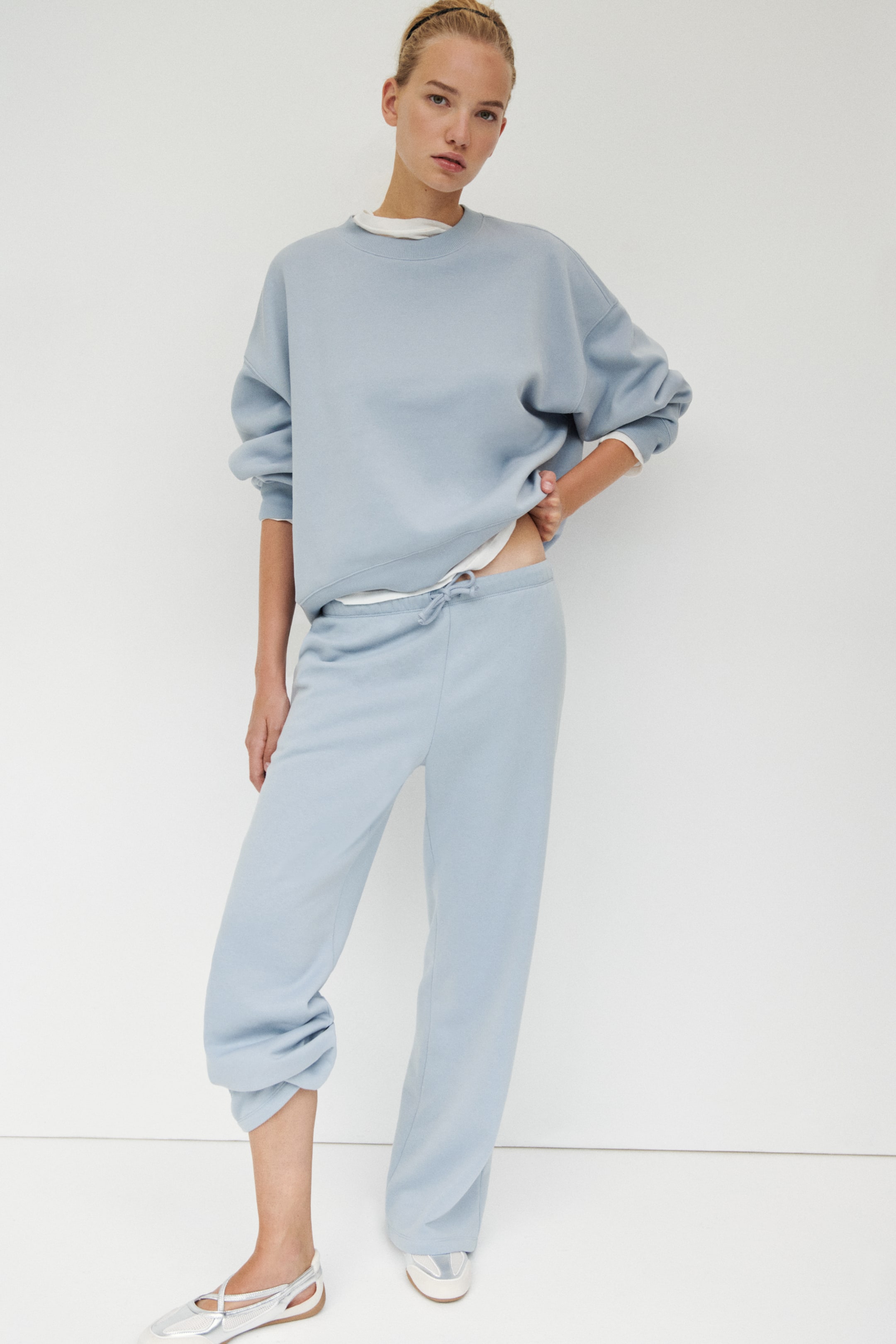 View larger image: Light blue, loose-fit joggers in a sweatshirt fabric featuring an elasticated, drawstring waist visible at the front. They present wide legs, with one leg styled with a gather.