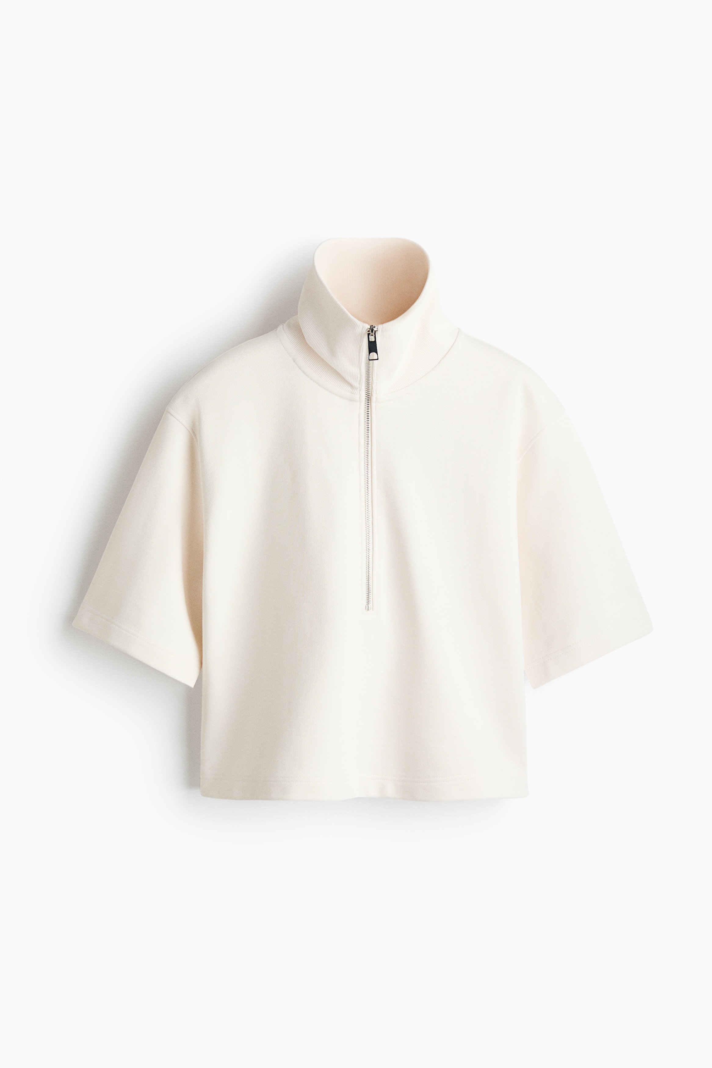 A white polo shirt in lightweight sweat fabric, featuring a half-zip collar, dropped shoulders, and elbow-length sleeves, is worn by the model. The shirt is layered over a red T-shirt and styled with beige shorts.