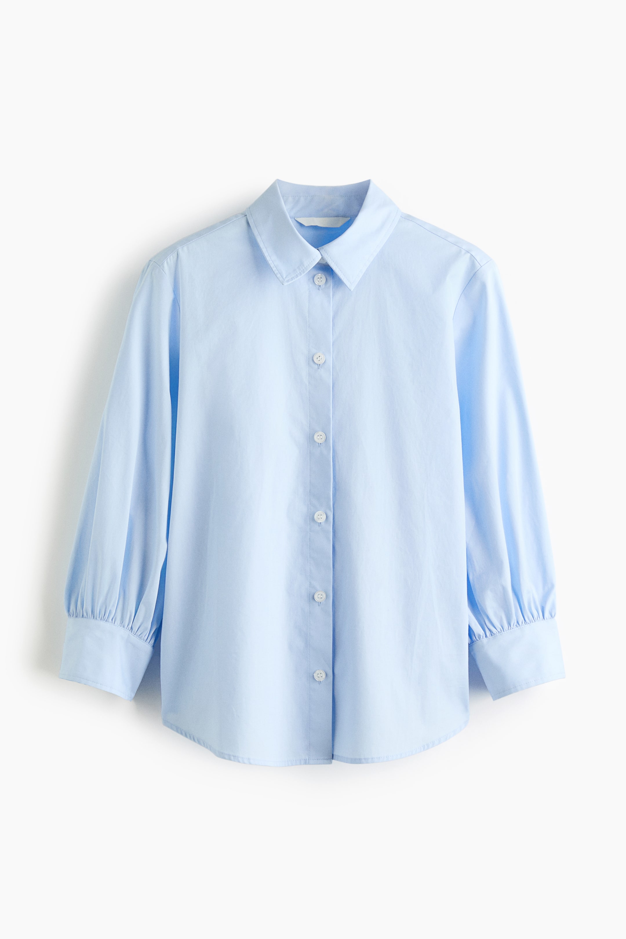 View larger image: A light blue shirt is showcased front-facing, featuring a pointed collar and a button-front placket with white buttons. It is crafted with long sleeves that culminate in gathered cuffs and a curved hemline.