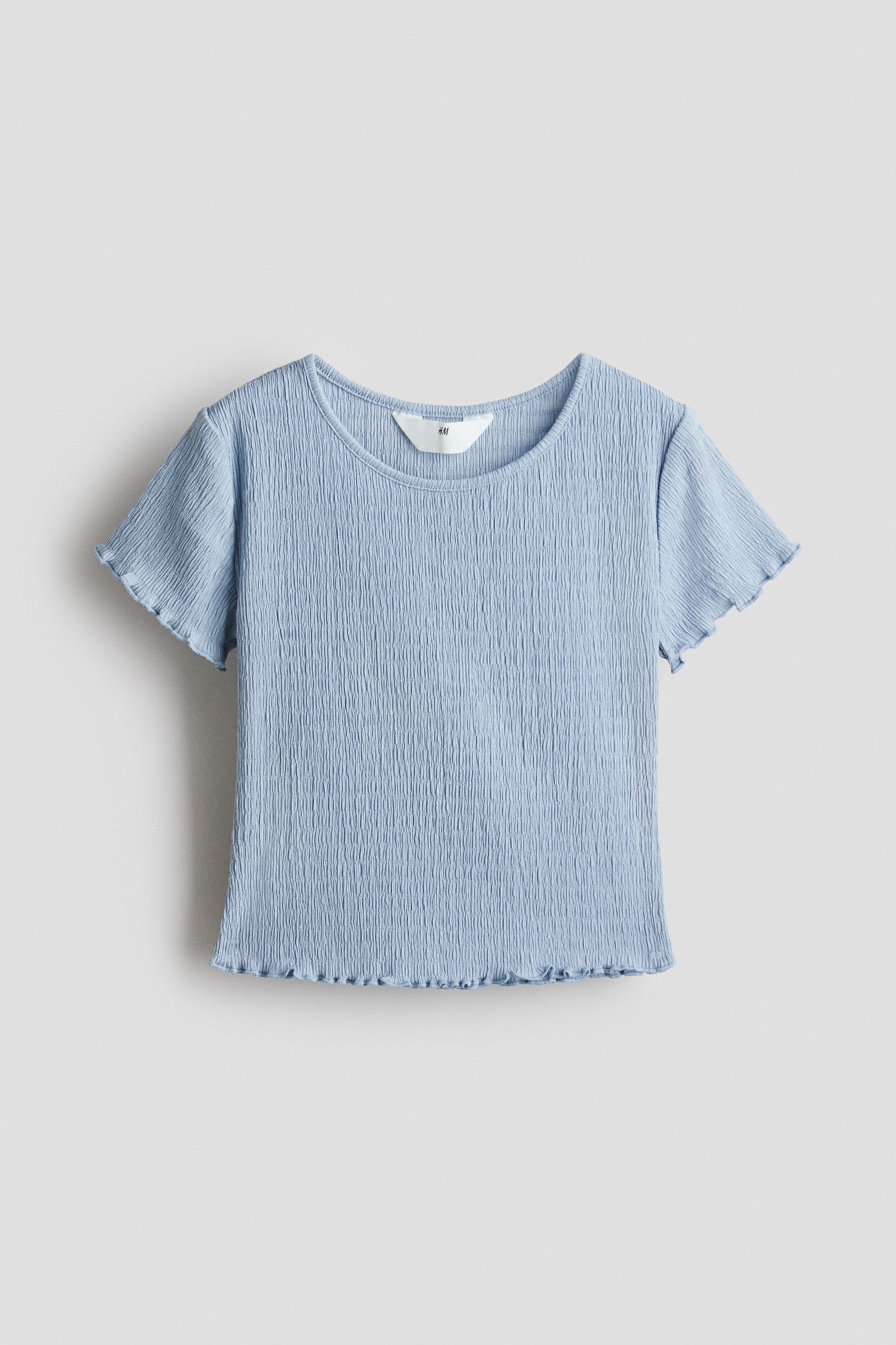 View larger image: A light blue T‑shirt is shown from the front, showcasing a crinkled texture across the body. It features a round neckline and short sleeves finished with lettuce‑edge hems. A matching lettuce‑edge finish also appears on the bottom hem, and a white H&M brand tag is visible on the inside of the back neckline.