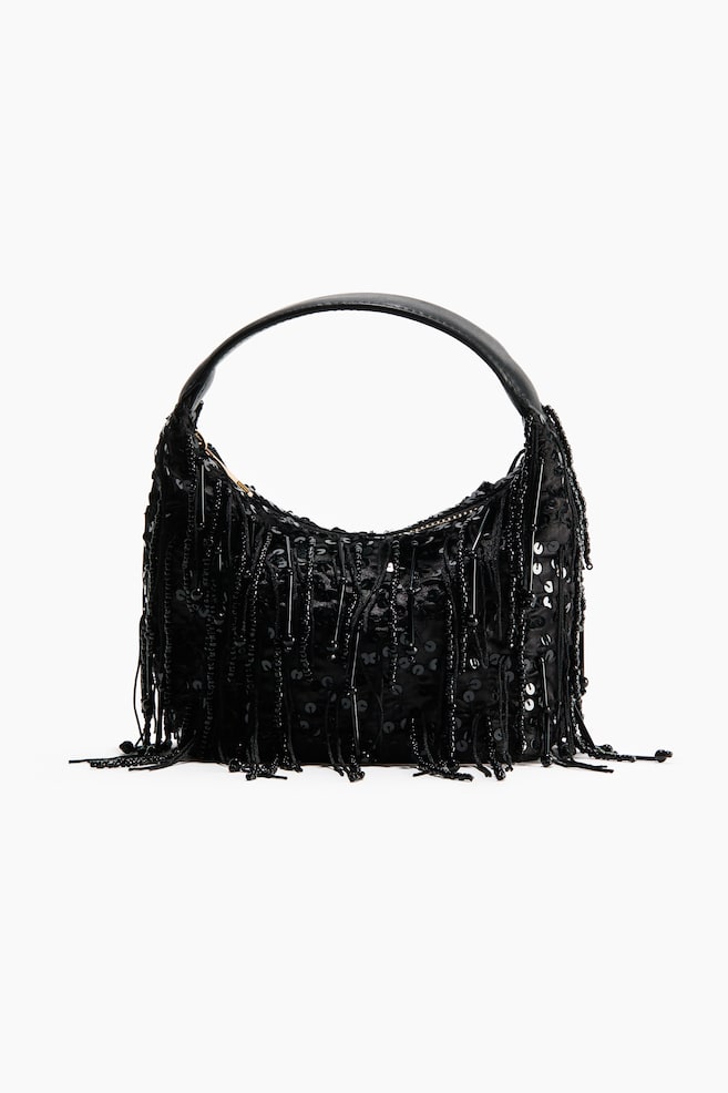 Eine schwarze Schultertasche im Hobo-Stil ist von vorne zu sehen und verfÃ¼gt Ã¼ber einen halbmondfÃ¶rmigen Korpus, der mit schimmernden schwarzen Pailletten bedeckt ist, sowie herabhÃ¤ngende StrÃ¤nge aus Perlenfransen. Ein glatter, geschwungener schwarzer Schulterriemen verlÃ¤uft bogenfÃ¶rmig Ã¼ber der Oberseite der Tasche. - 1