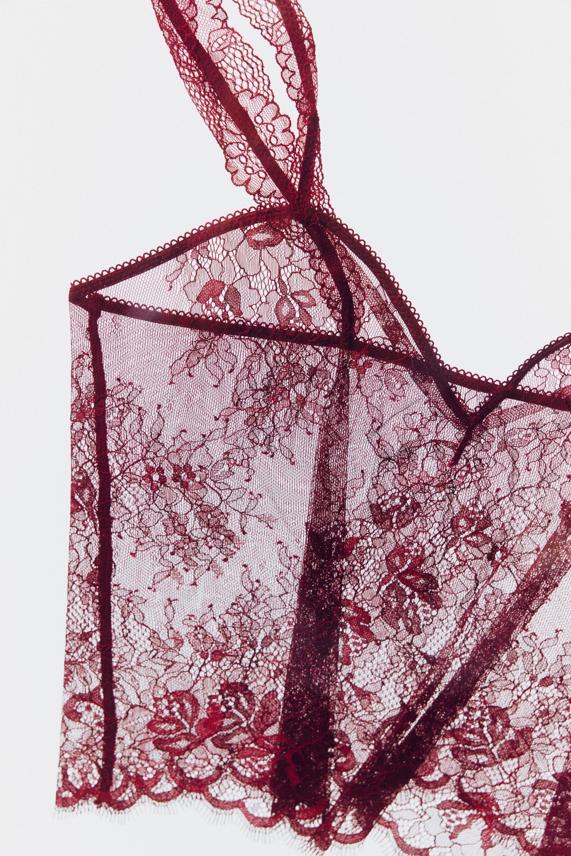 View larger image: A deep red lace bralette featuring intricate floral patterns, scalloped edges, delicate lace straps, and structured cup detailing.