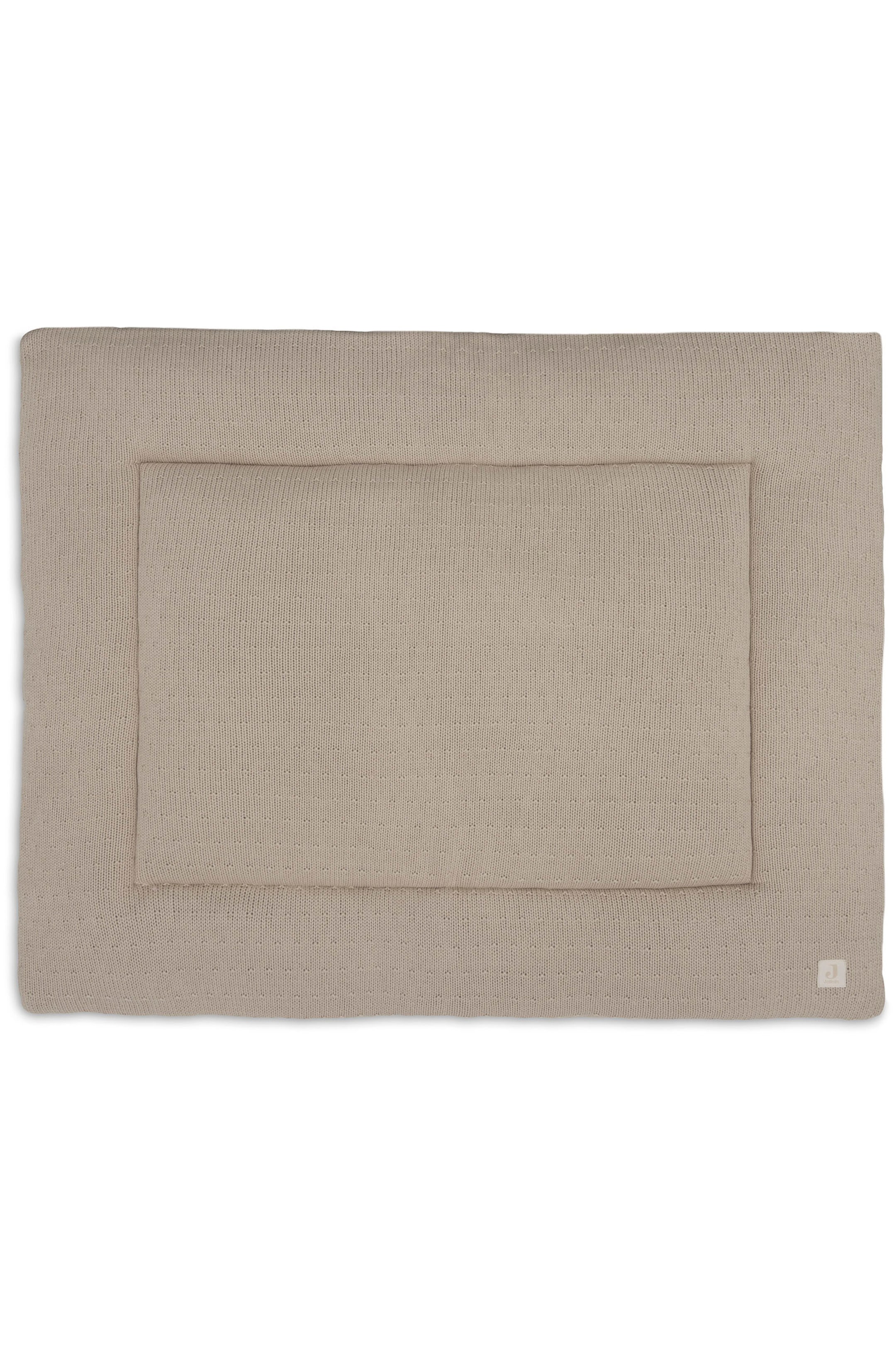 Agrandir l'image: Un tapis de parc rectangulaire couleur sable est posé à plat, mettant en valeur sa texture en maille fine et une section rectangulaire surpiquée en relief au centre. Une petite étiquette de marque carrée est cousue dans le coin inférieur droit.