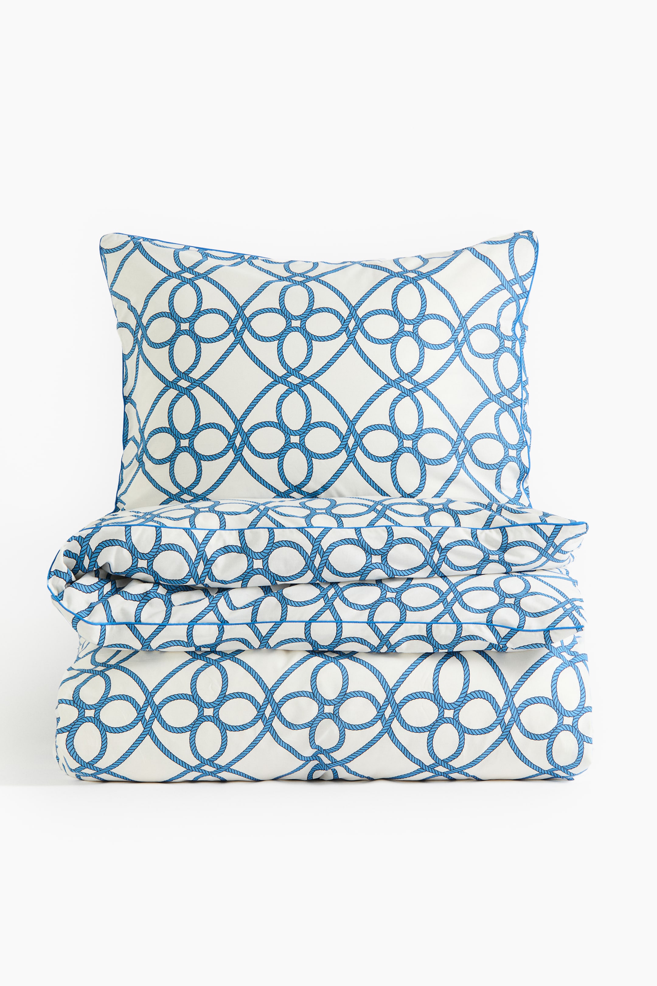 Prikaži veću sliku: Сет беле навлаке за поплун карактерише плави узорак испреплетених конопа. Јастук стоји усправно, а усклађена навлака за поплун је испод њега сложена — обоје су окренута према напред.