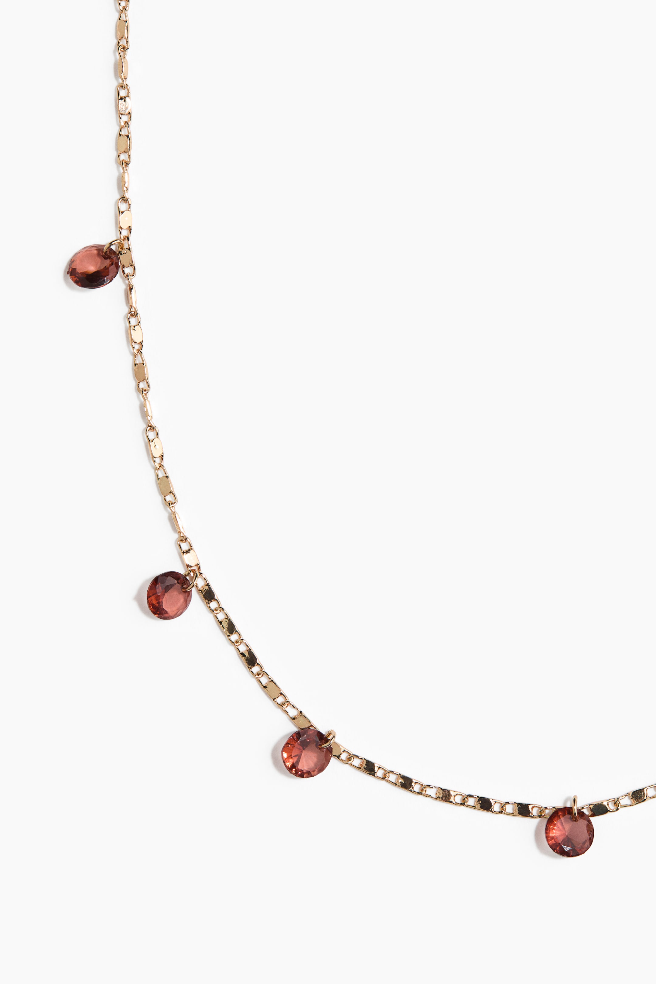 Agrandir l'image: Un collier chaîne rectangulaire plat de ton doré affiche plusieurs pierres précieuses facettées d'un brun rougeâtre profond, réparties régulièrement le long de sa longueur.