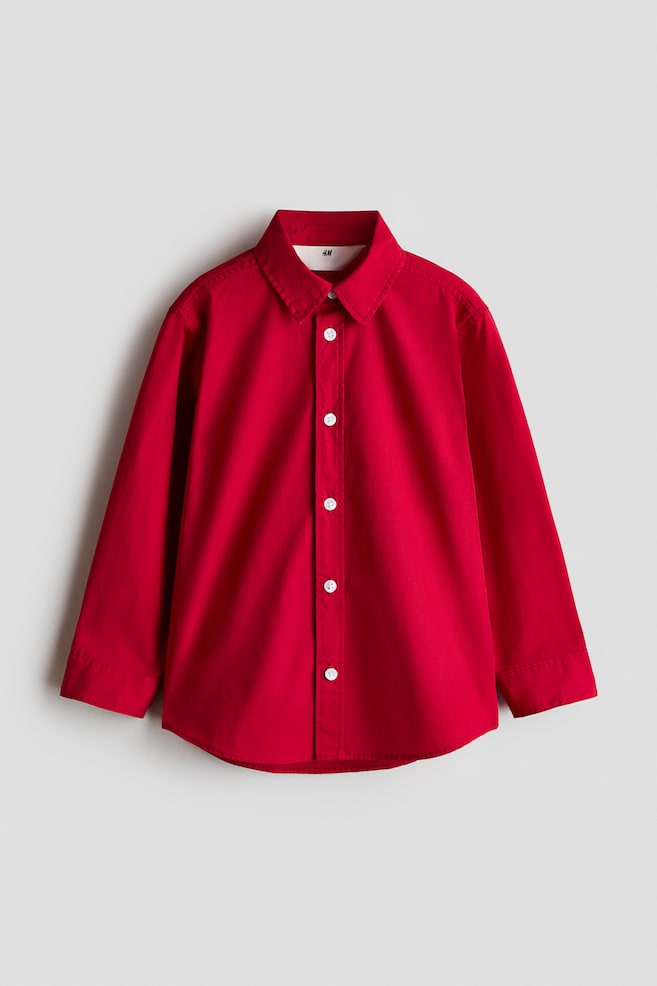 A red long-sleeved button-down shirt is facing front, showcasing a turn-down collar, white buttons down the front, and long sleeves with cuffs. The shirt is displaying a gently rounded hem. - 1