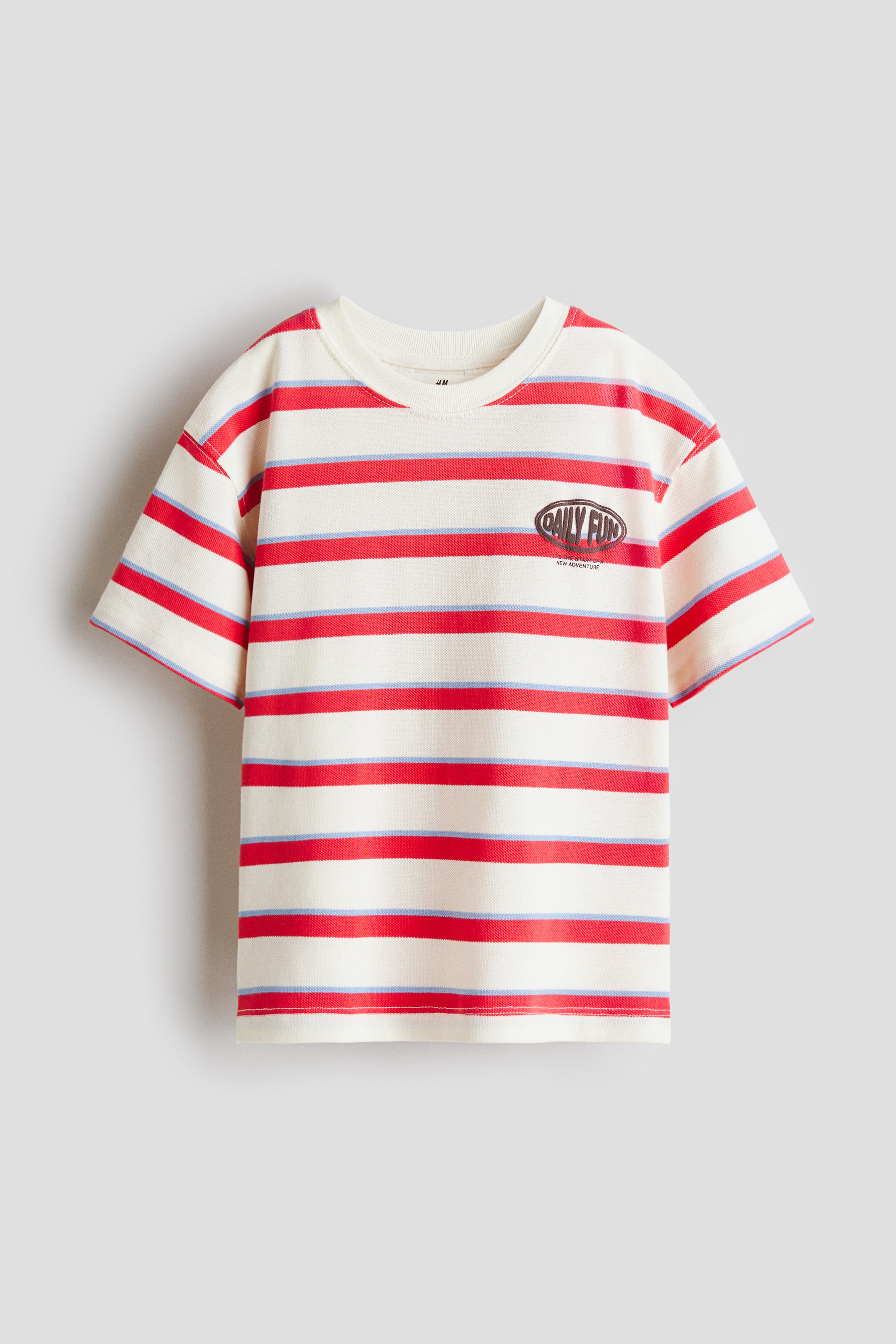 View larger image: This t-shirt showcases its FRONT, boasting a ribbed crew neck and a cream base adorned with alternating wide red and thin light blue horizontal stripes. An oval graphic with the text "DAILY FUN" is printed on the left chest.