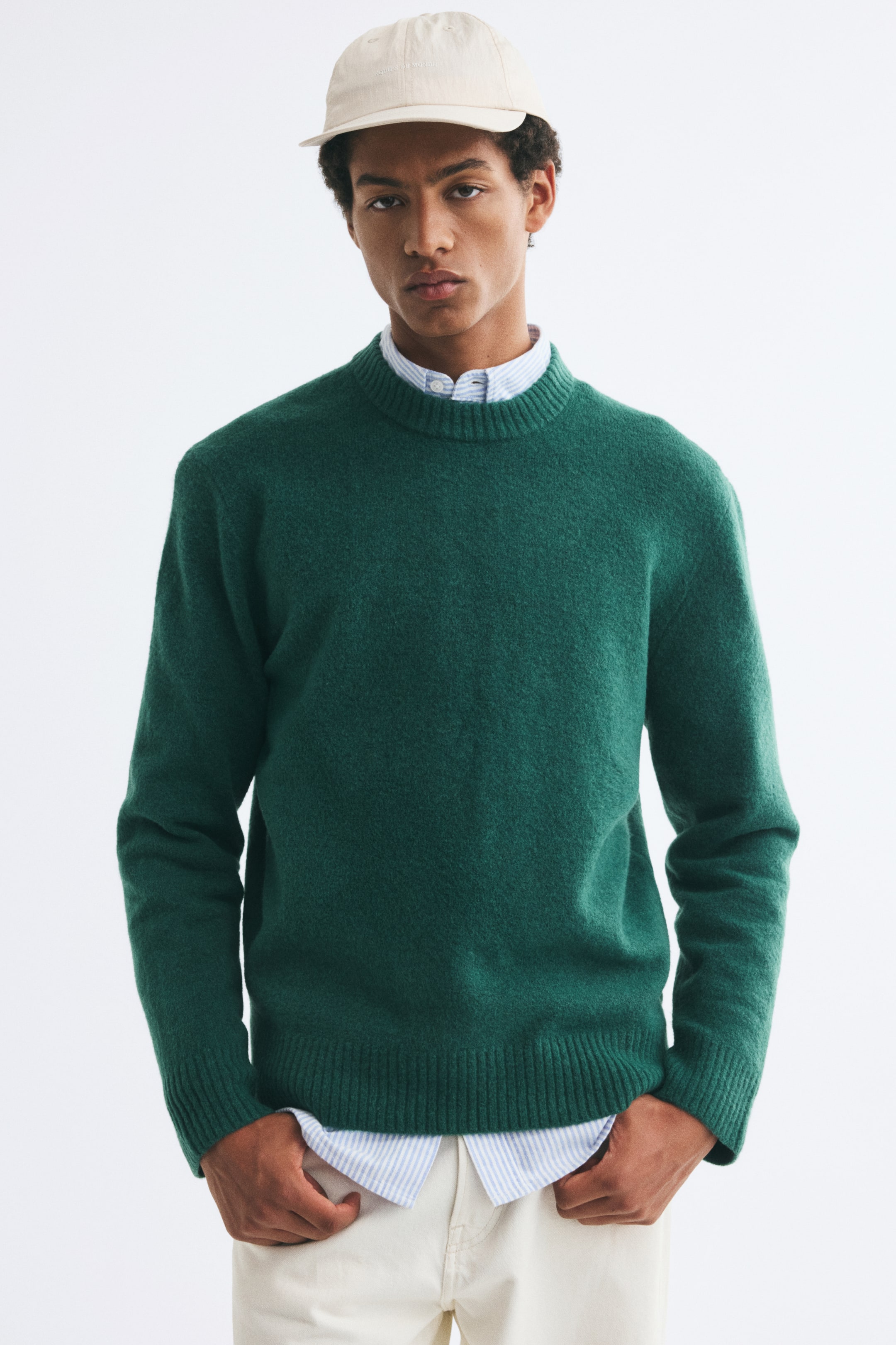 View larger image: A green sweater in a soft brushed knit is worn by the model, layered over a blue and white striped collared shirt. The sweater features a regular fit with a round rib-trimmed neckline and ribbed detailing at the cuffs and hem.