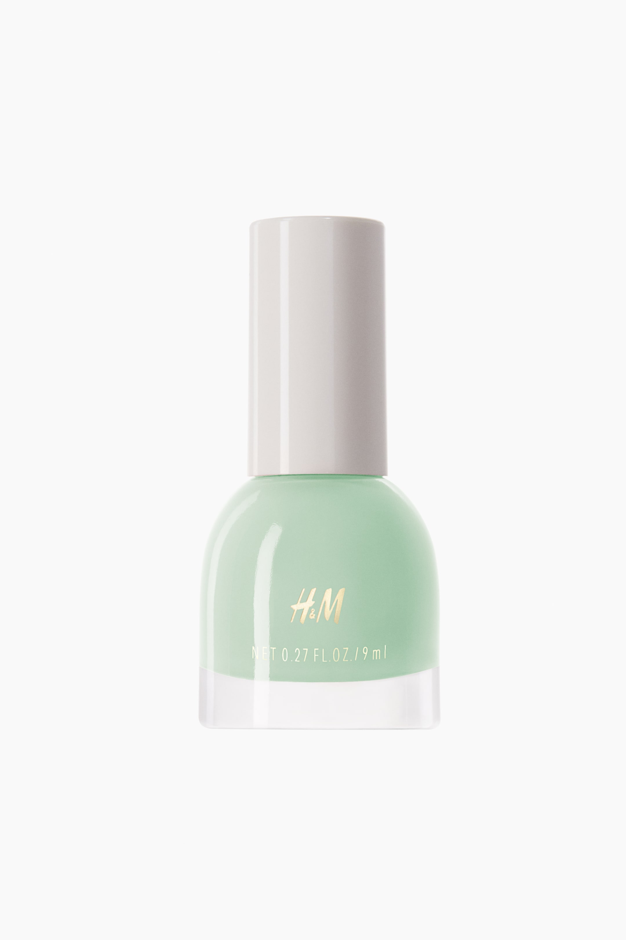 View larger image: The nail polish showcases a mint green hue in a transparent glass bottle, topped with a light-toned, cylindrical cap, displaying "H&M" and "NET 0.27 FL. OZ. / 9 ml" on the front.