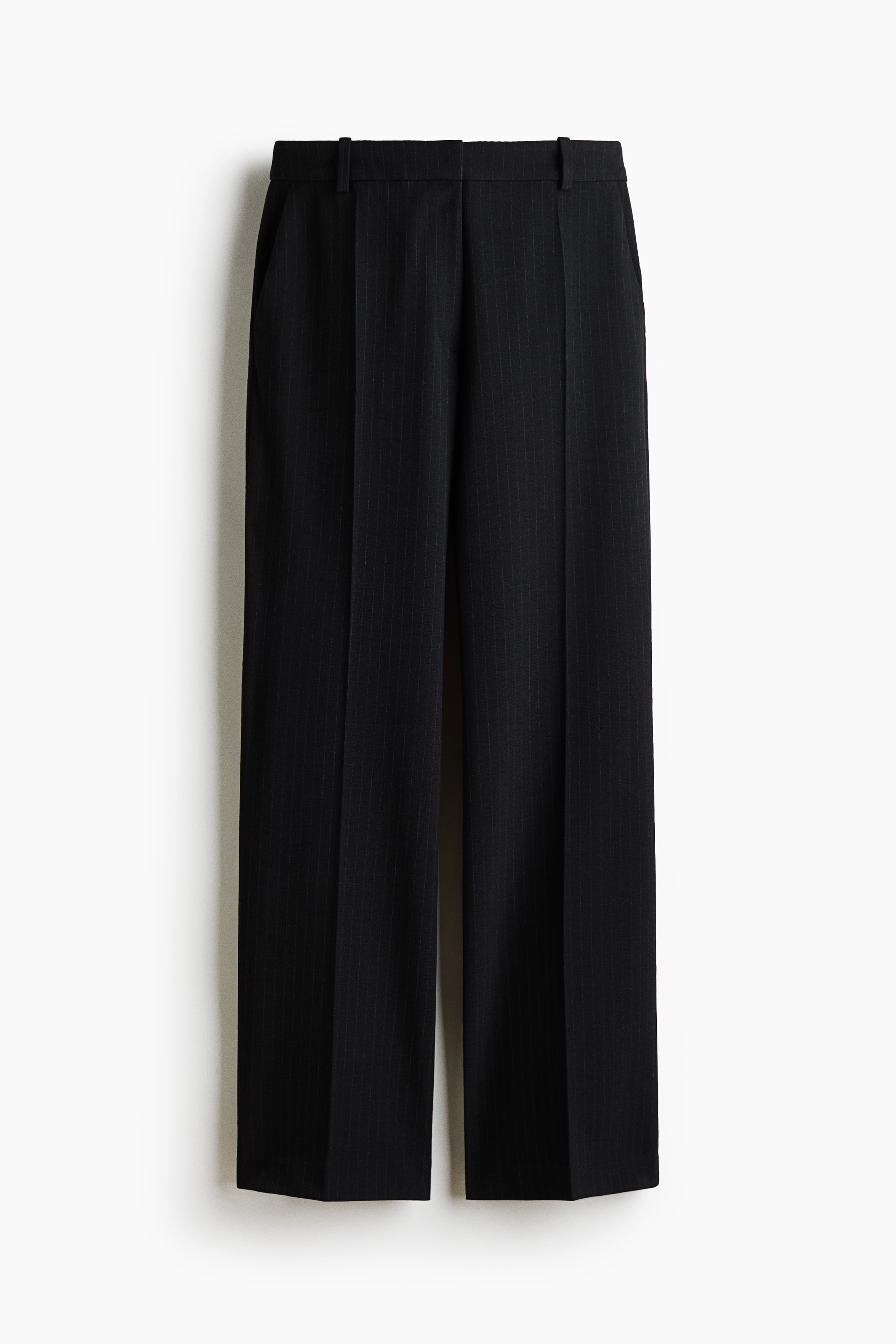 MaÃgeschneiderte schwarze Nadelstreifenhose mit Bootcut-Bein und BÃ¼gelfalten vorn, getragen von dem Model, das mit Ã¼bereinandergeschlagenen Beinen sitzt. Die Hose ist mit einem passenden Nadelstreifenblazer, einem aufgeknÃ¶pften weiÃen Hemd und einem schwarzen Stiefelettenschuh mit spitzer Spitze und Absatz kombiniert.