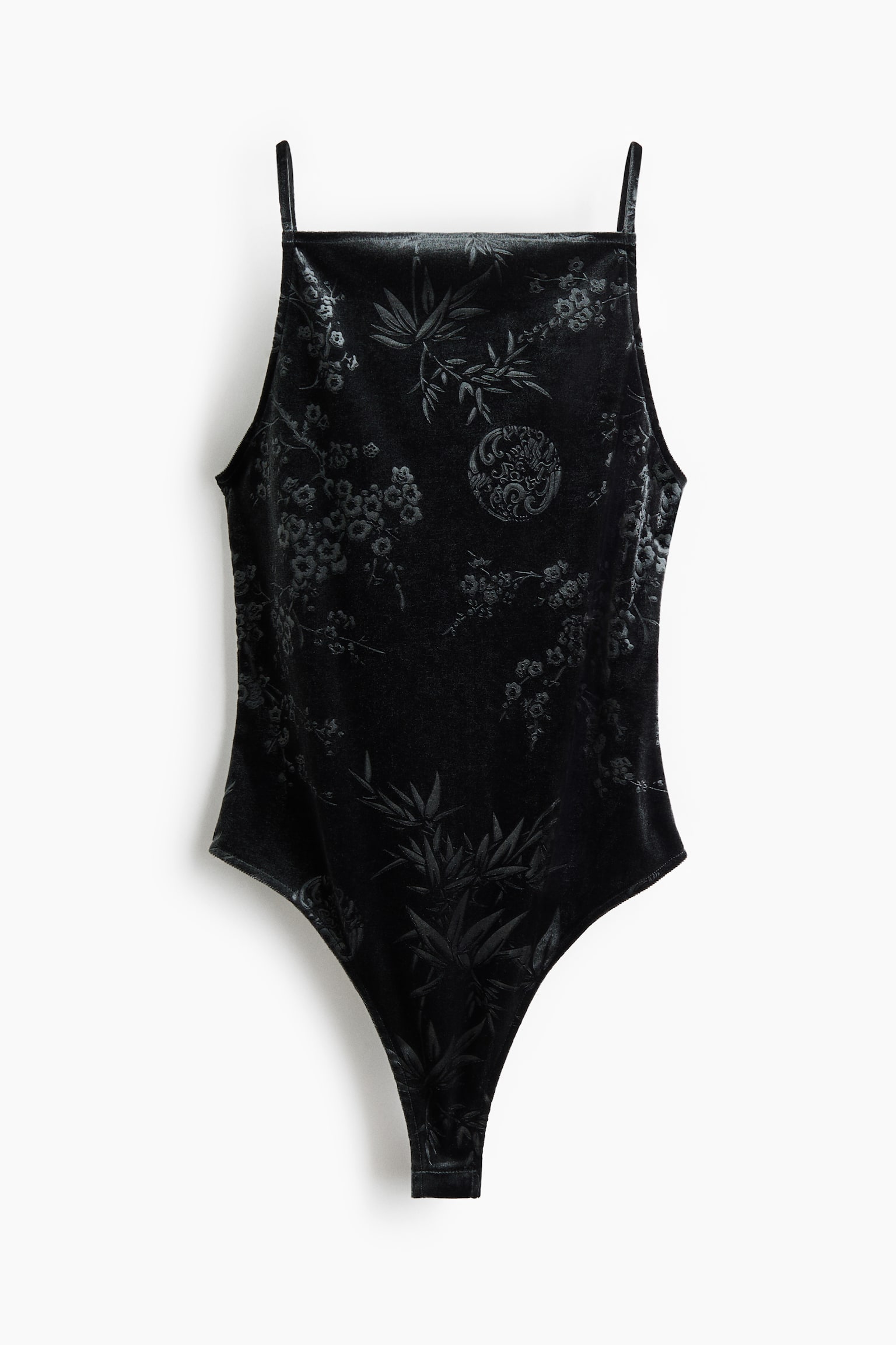 A black velvet bodysuit is shown from the front, featuring a subtle jacquard pattern with bamboo leaves and floral motifs. The bodysuit features a square neckline, thin spaghetti straps, and high-cut leg openings.