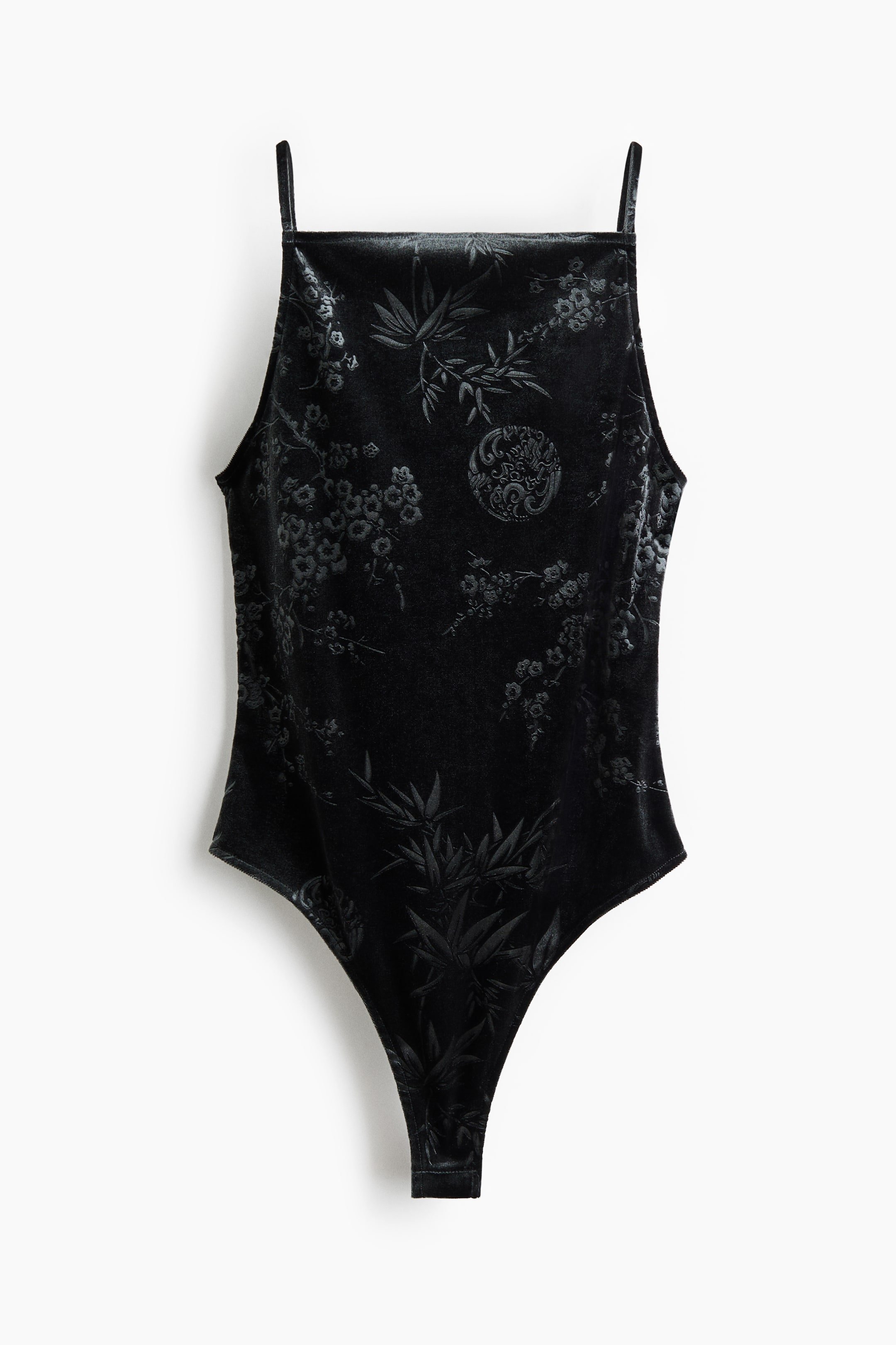 View larger image: A black velvet bodysuit is shown from the front, featuring a subtle jacquard pattern with bamboo leaves and floral motifs. The bodysuit features a square neckline, thin spaghetti straps, and high-cut leg openings.