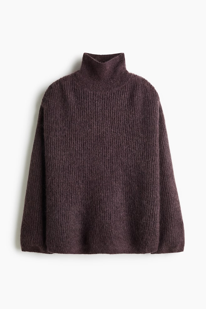 Un jersey oversize de mezcla de mohair y canalé se muestra de frente, destacando un color ciruela oscuro, cuello alto, hombros caÃdos y mangas largas. El jersey presenta un punto suave y texturizado, con un fino ribete acanalado en los puños y el bajo. - 1