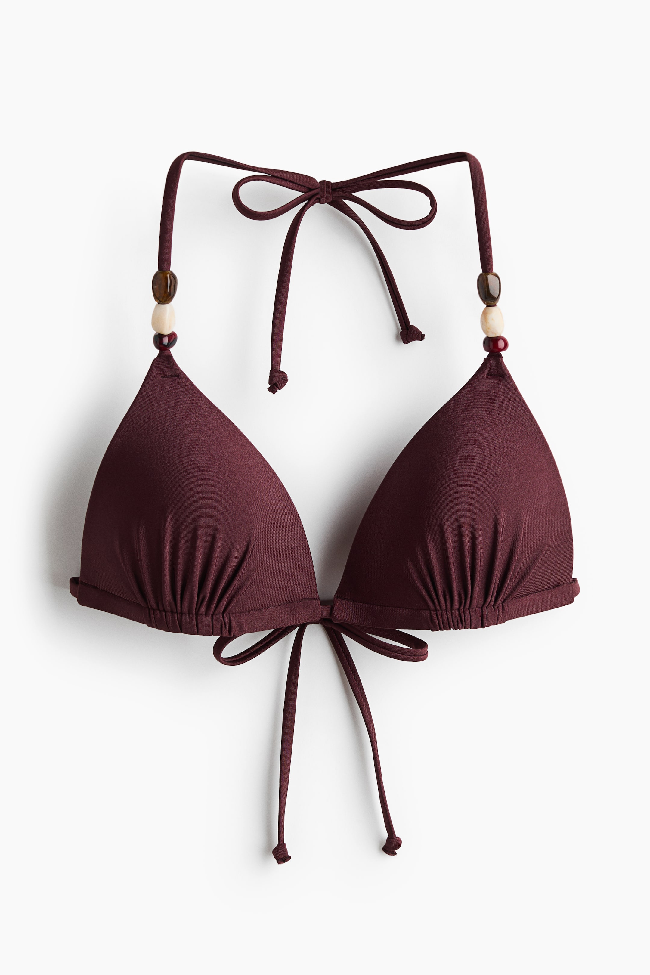 Grotere afbeelding bekijken: Een bordeauxrode driehoekige bikinitop is zichtbaar aan de voorkant, met cups die aan de onderkant gerimpeld zijn. Dunne bandjes, versierd met bruine, beige en rode kralen op het haltergedeelte, worden vastgeknoopt in de nek en op de rug.