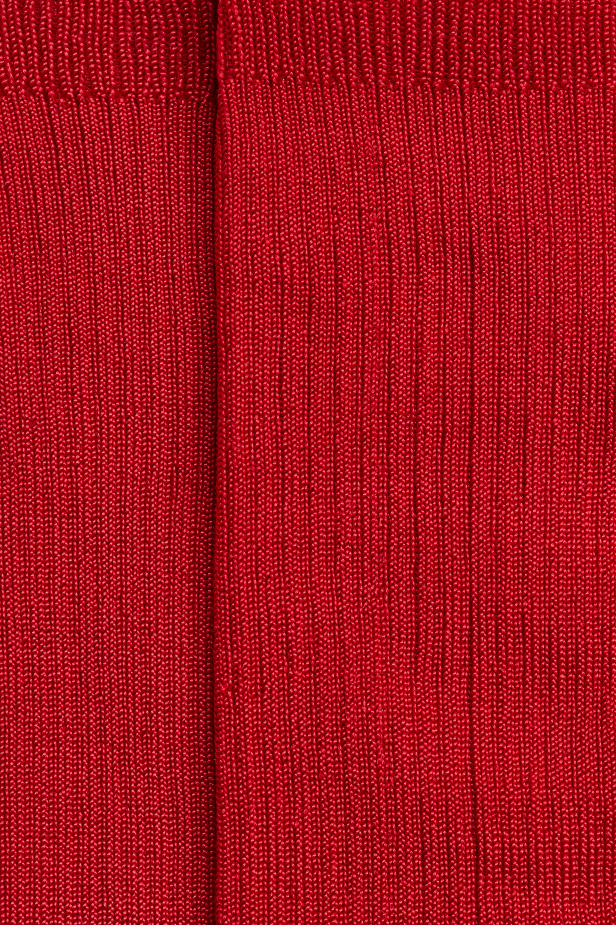 View larger image: Red ribbed hosiery is displayed, featuring fine vertical ribs throughout. A wider, denser ribbed cuff is visible at the top, alongside a subtle central seam running vertically.