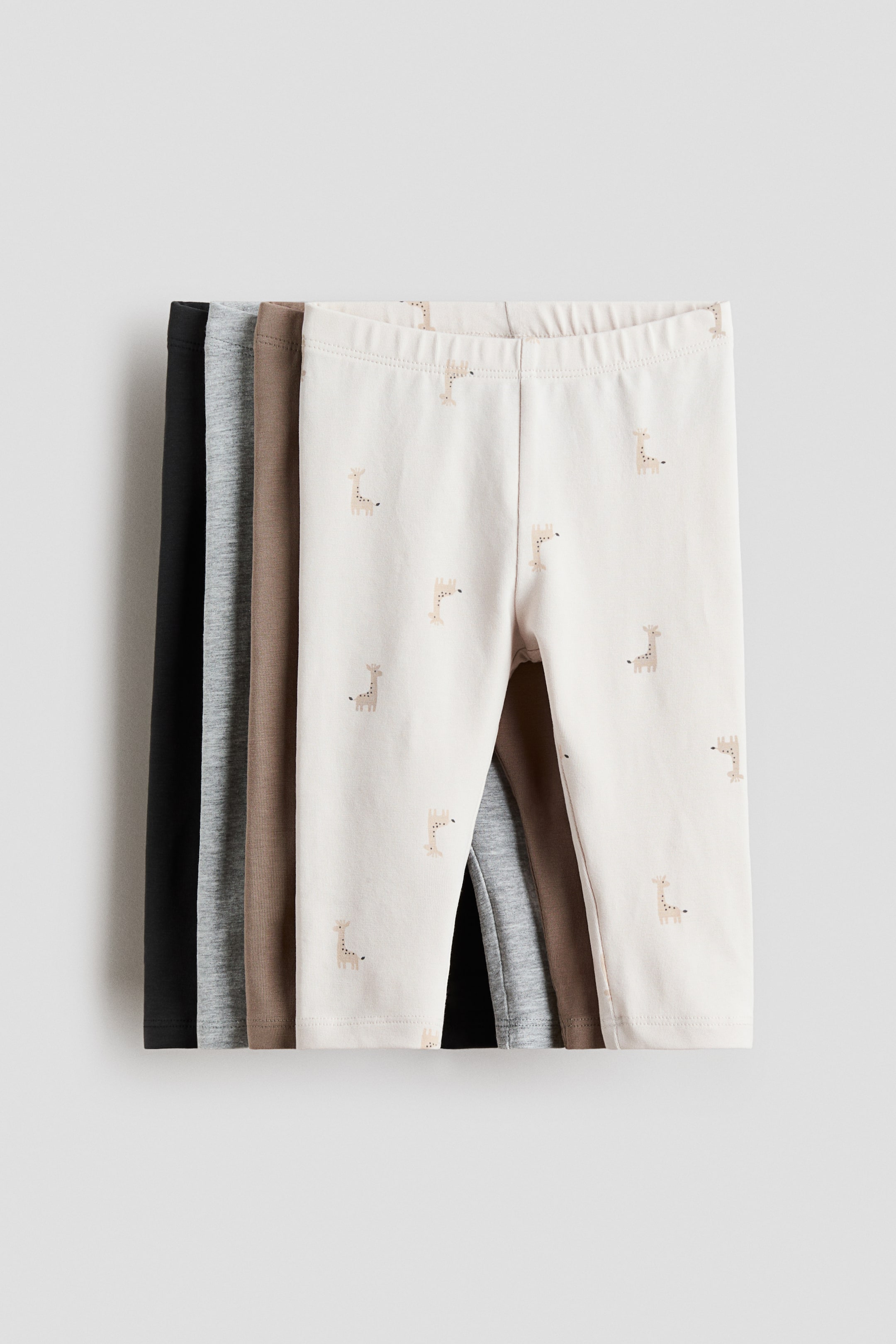 View larger image: The frontmost pair, facing FRONT, is showing a light beige color with a pattern of small, light brown giraffe figures and is featuring a covered elastication at the waist. 