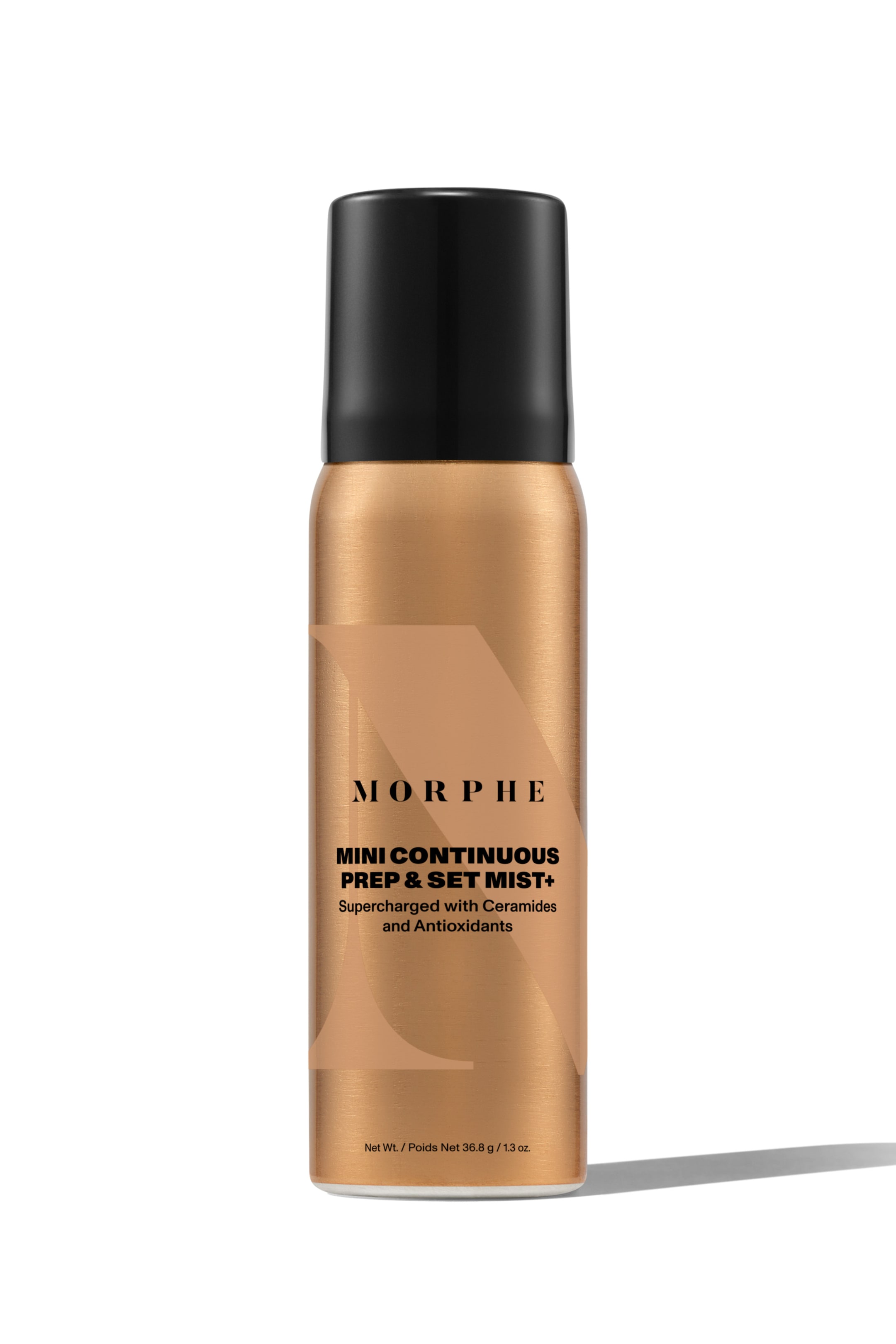 Se større billede: En Morphe Mini Continuous Prep & Set Mist+ sprayflaske står oprejst, vendt fremad. Den cylindriske, metalliske bronzebeholder har en sort hætte og sort tekst, der identificerer mærket og produktdetaljerne, sat mod et subtilt, lysere bronze geometrisk design.