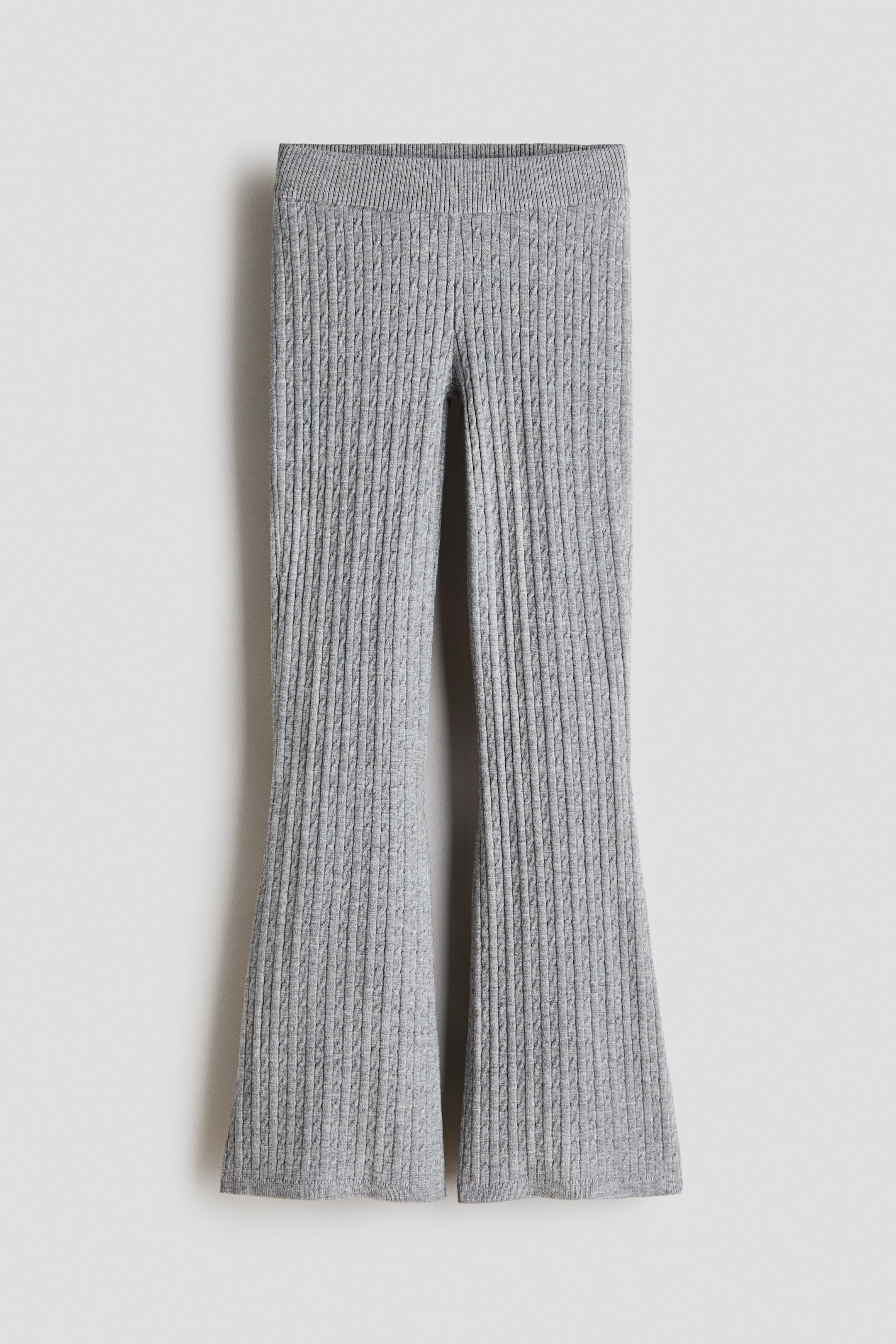 View larger image: Grey ribbed knit trousers are showcased in a flat-lay, front-facing view, featuring a wide ribbed waistband and a vertical ribbed texture throughout the legs, which flare out from the knee.