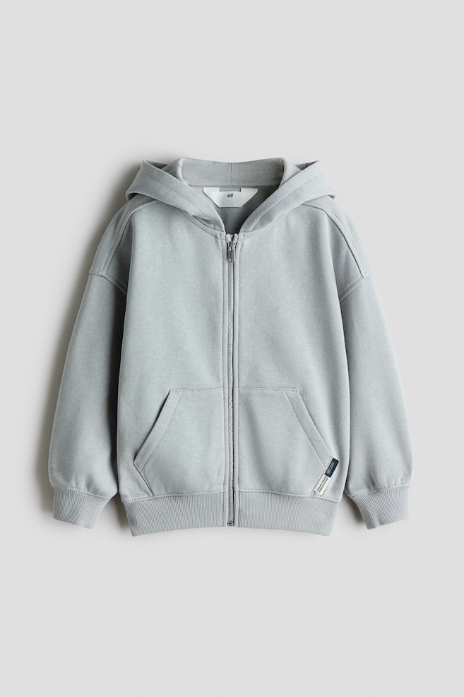 Ein hellgrauer Hoodie mit ReiÃverschluss ist von vorne zu sehen und zeigt einen durchgehenden MetallreiÃverschluss, eine Kapuze und Ã¼berschnittene Schultern. Er verfÃ¼gt Ã¼ber geteilte KÃ¤ngurutaschen im unteren Vorderbereich, RippbÃ¼ndchen an den Ãrmeln, einen gerippten Saum und ein kleines gewebtes Label an der linken Tasche. - 1