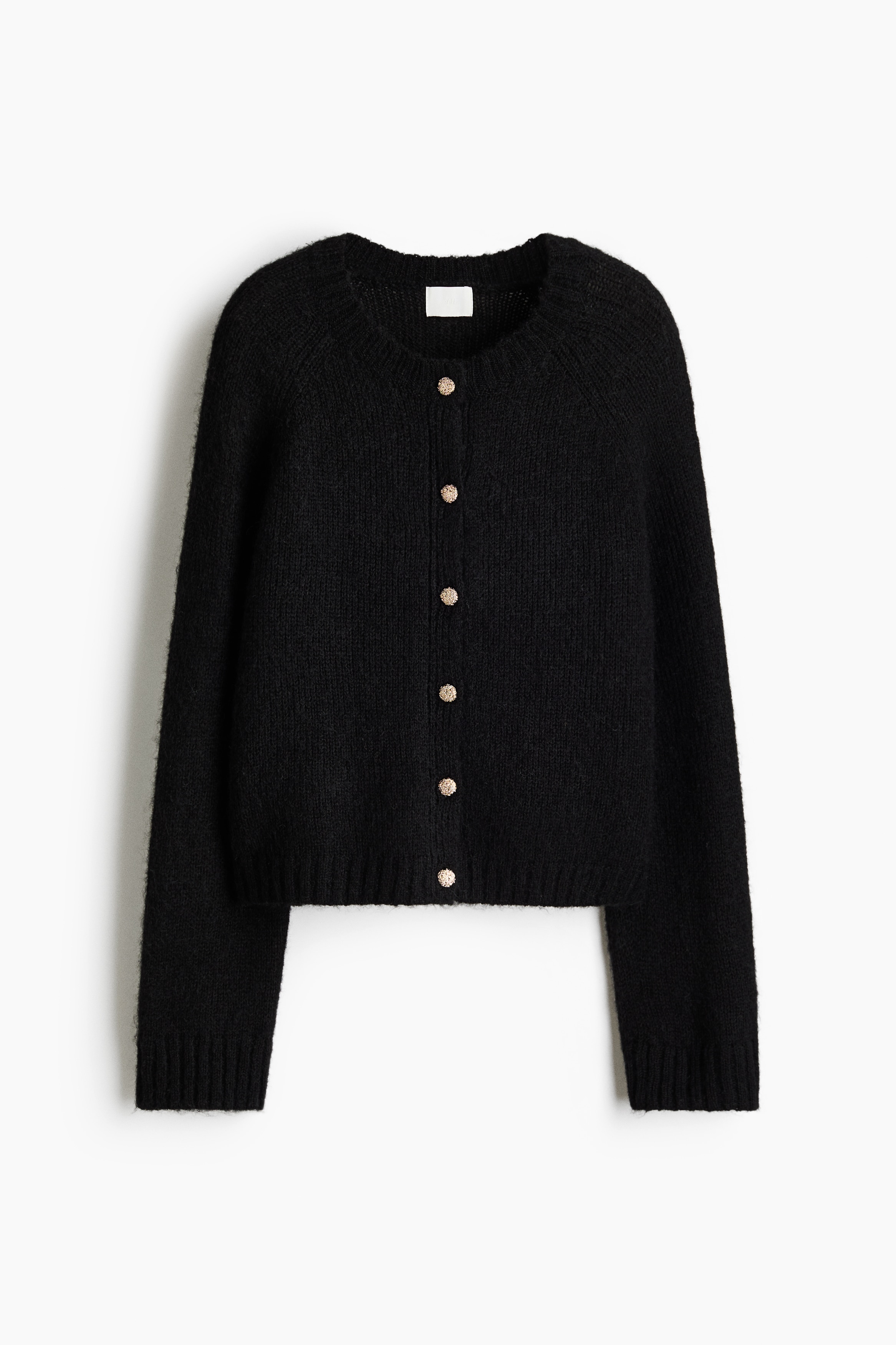The model is wearing a black soft-knit cardigan with textured gold-tone buttons. The cardigan features a round neckline with rib trim and raglan sleeves.