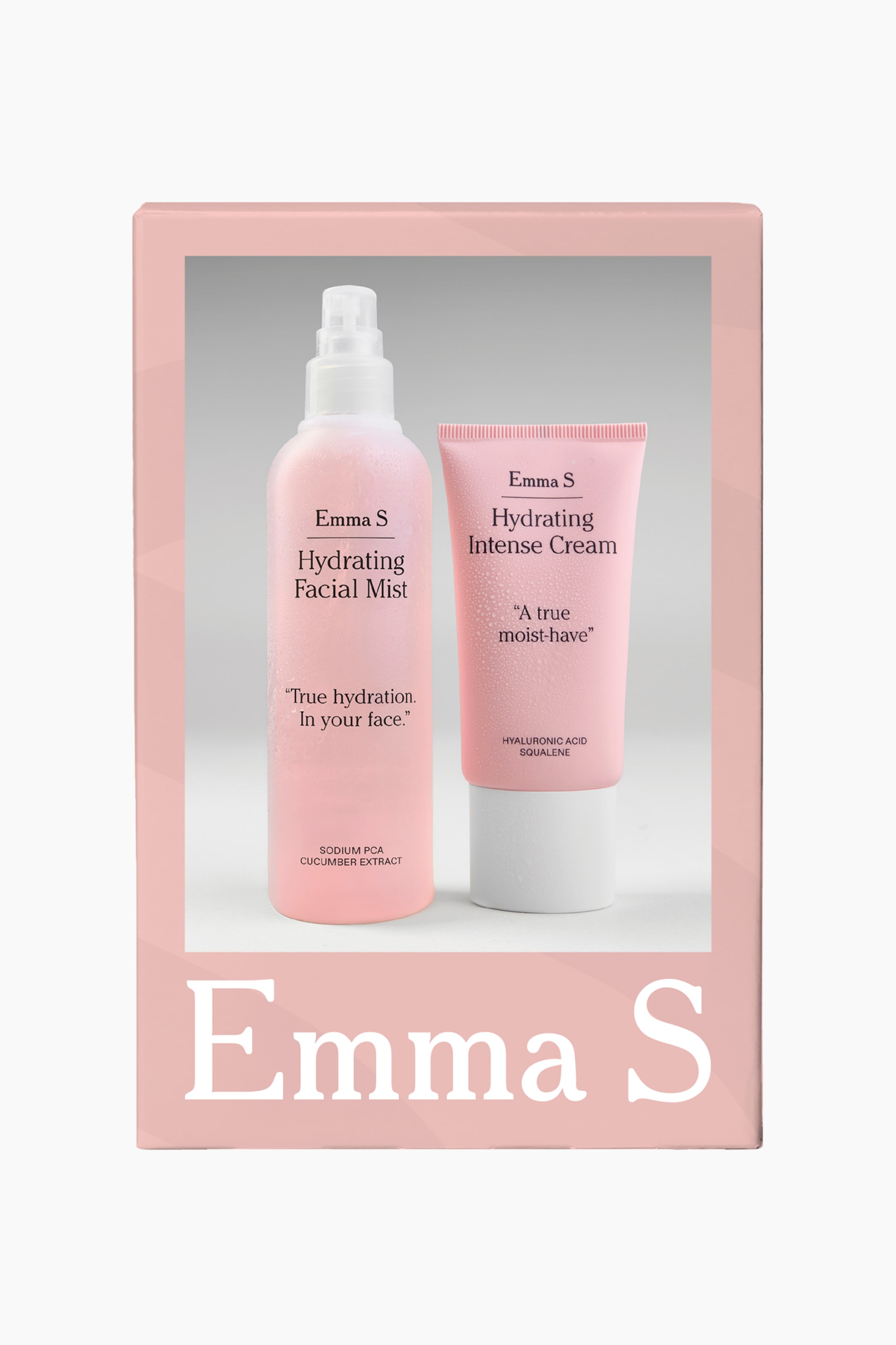 Visa större bild: En rosa presentask visar upp ett hudvårdskit som innehåller en hög sprayflaska med "Hydrating Facial Mist" och en tub med klämfunktion av "Hydrating Intense Cream" från varumärket Emma S. Båda de ljusrosa produkterna står upprätt i lådans rektangulära fönster och visar fina kondensdroppar på sina ytor.