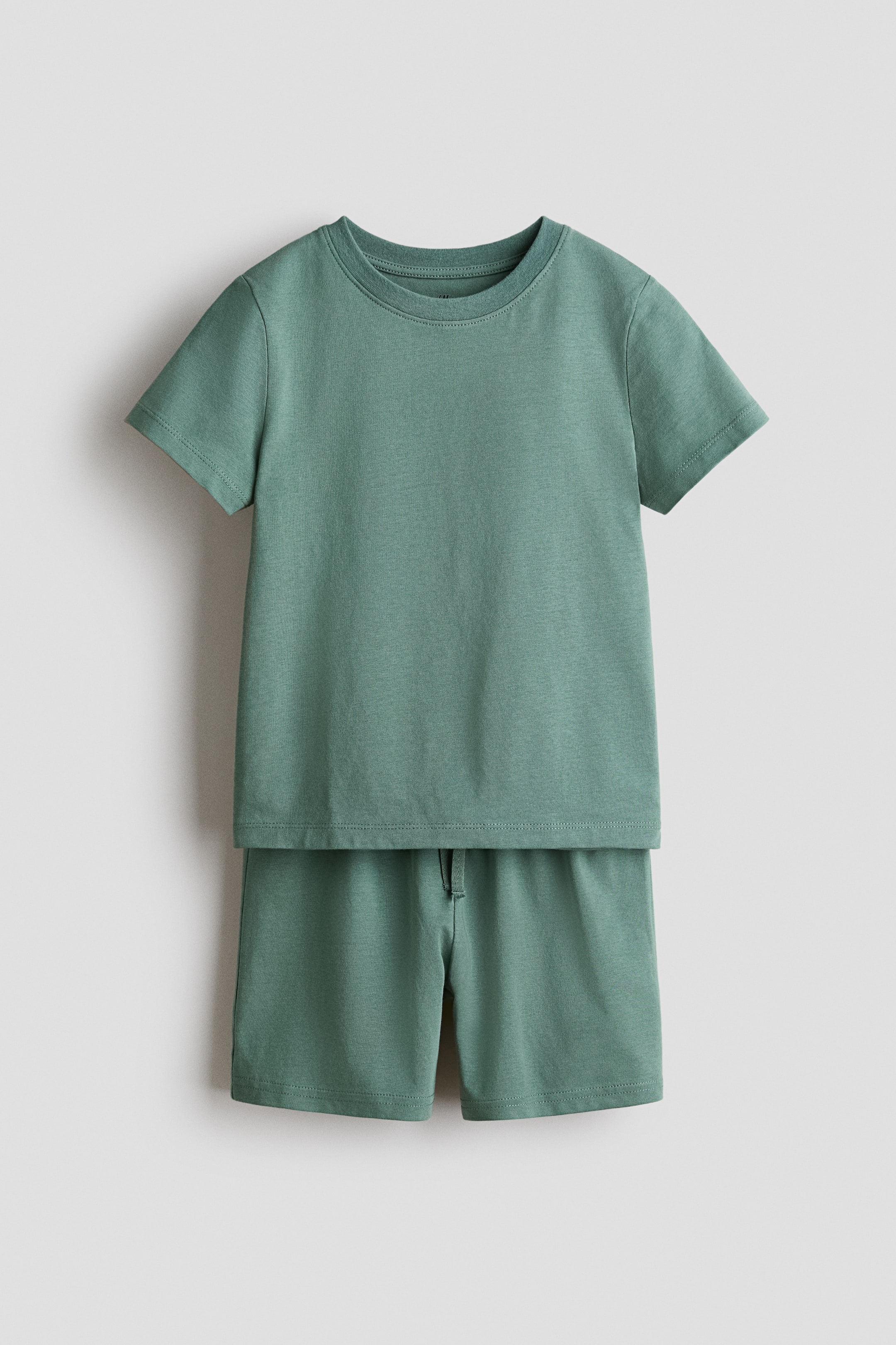 View larger image: A set comprising a t-shirt and pair of shorts in soft cotton jersey is displayed front-facing in a muted green colour. The t-shirt features a round, ribbed neckline and a straight-cut hem, while the shorts boast an elasticated, drawstring waist.