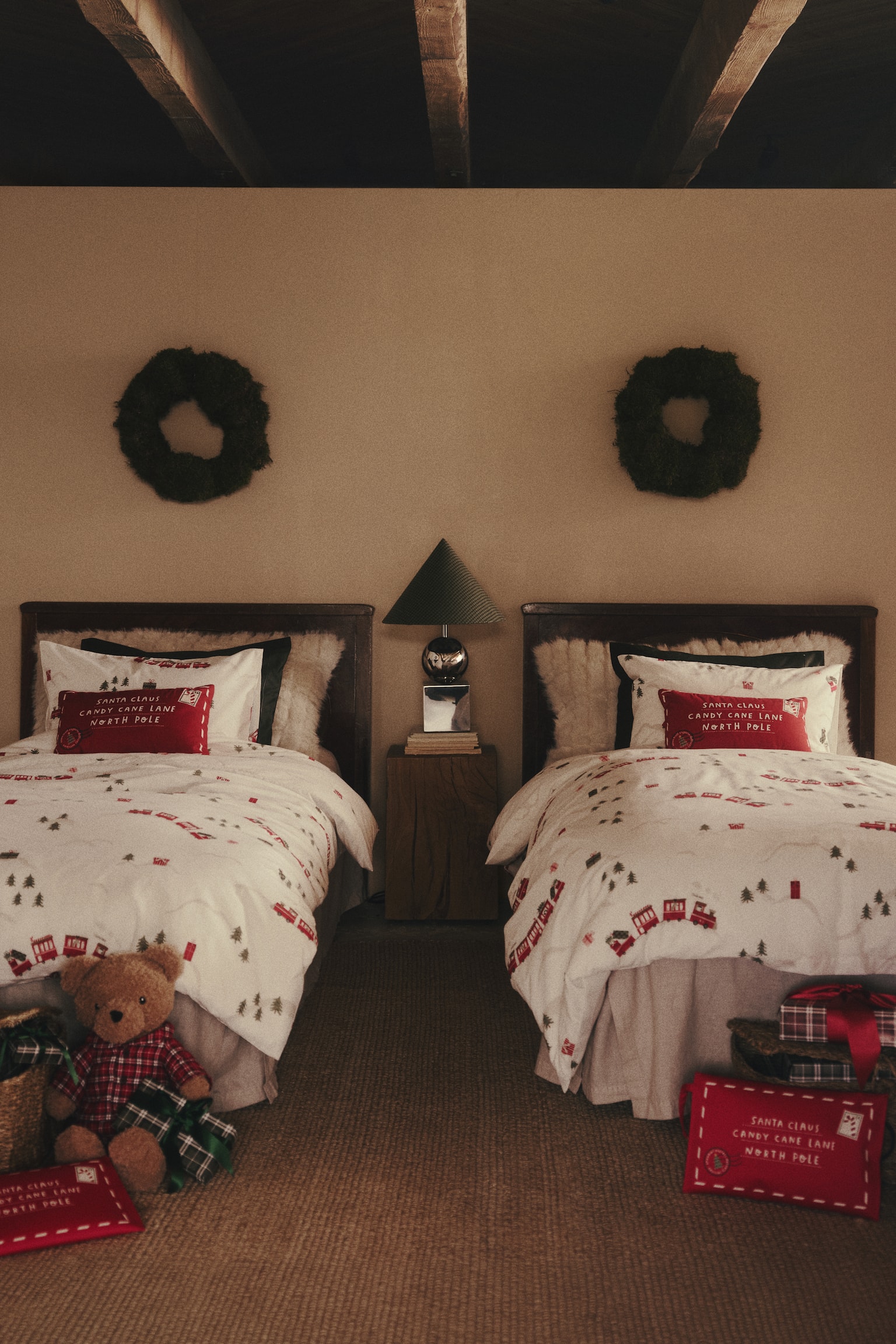 A cream-coloured quilt cover set is dressing two single beds, displaying an all-over festive print of red trains and green pine trees. Each bed features a matching patterned pillowcase positioned at the headboard. - 1