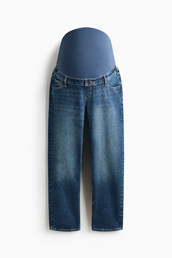 Diese Umstandsjeans, von vorne gezeigt, bestehen aus blauem Denim in mittlerer Waschung mit einem breiten, dehnbaren blauen Jersey-Bund-Einsatz am oberen Rand. Das Design zeigt einen angedeuteten Hosenschlitz mit einem einzelnen Knopf, Five-Pocket-Details und gerade, knÃ¶chellange Beine, die zum Saum hin leicht schmal zulaufen. - 1
