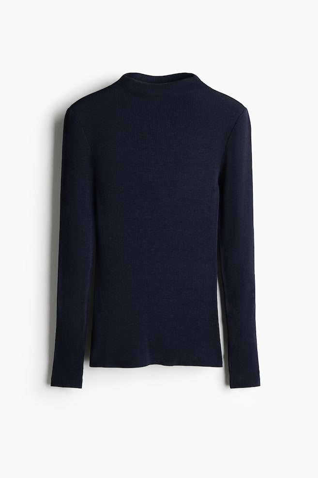 A dark navy blue, long-sleeved, ribbed mock-neck top is displayed in a fitted silhouette with a high, clean-finished neckline and long sleeves, facing front. The top features a finely textured rib-knit pattern throughout and finishes with a straight hem. - 1