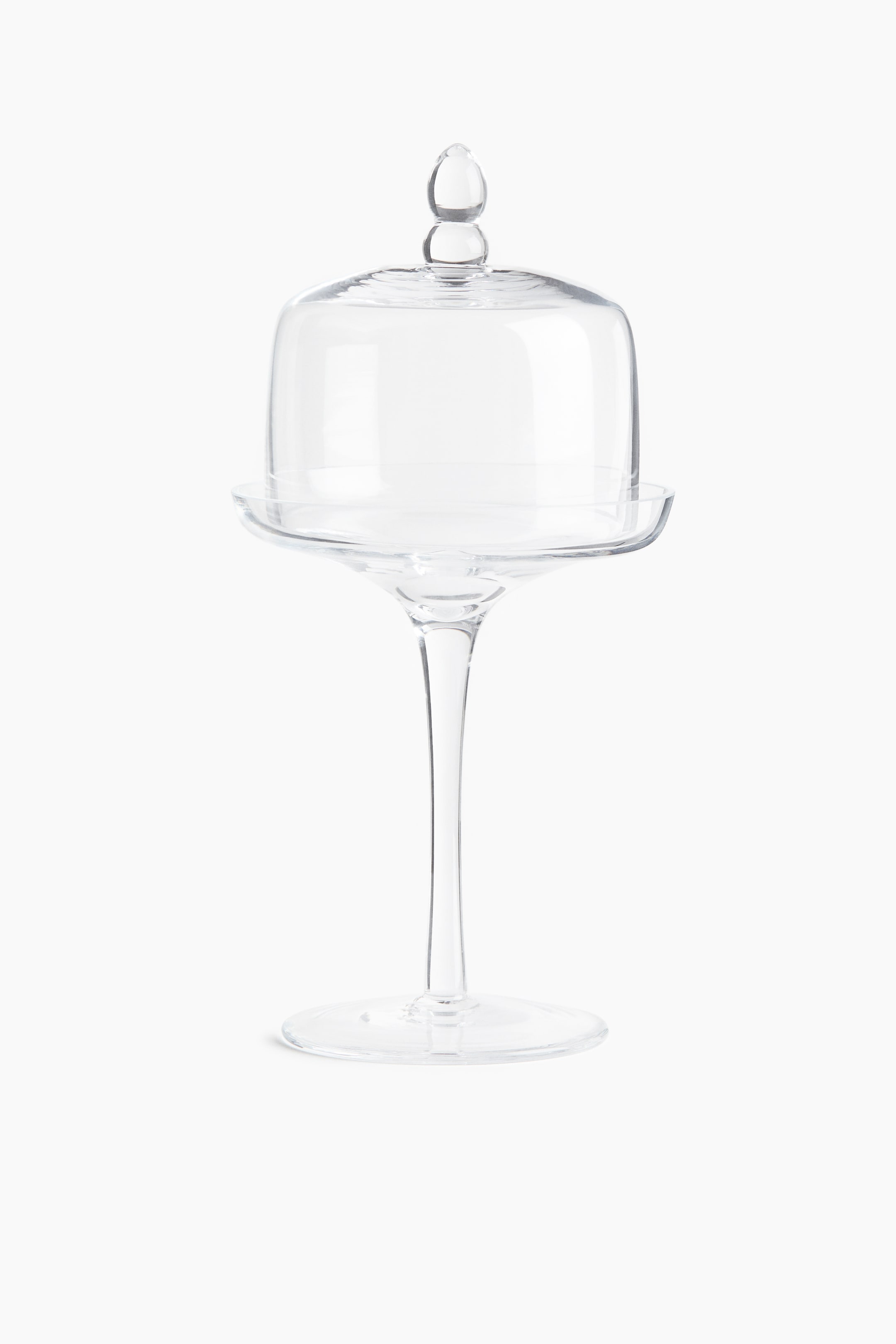 View larger image: A clear glass pedestal dessert stand is facing front, featuring a tall, slender stem rising from a flat circular base to support a shallow plate. A matching clear glass dome lid with a double-bulb finial handle is resting on top of the plate.