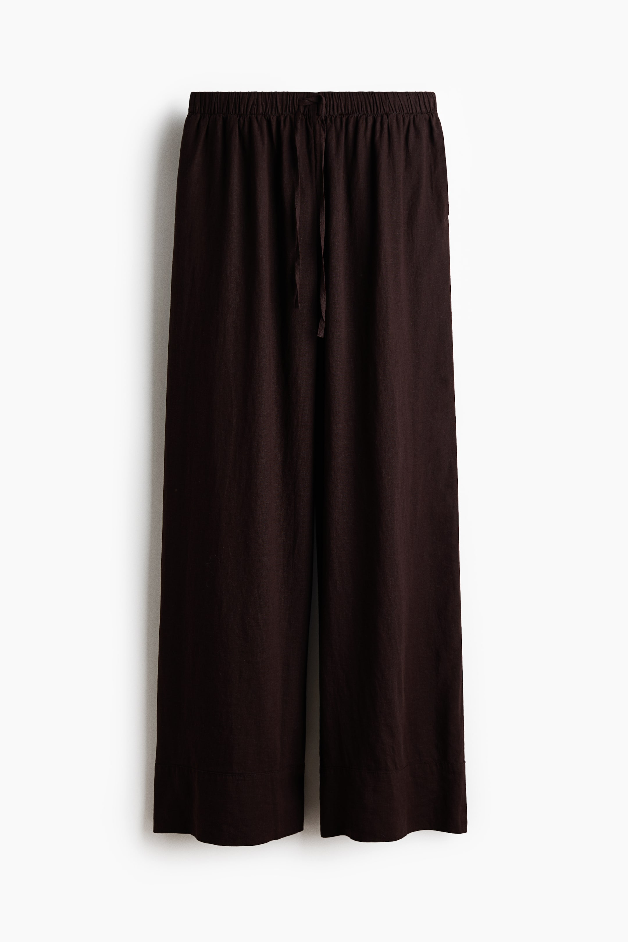 View larger image: Dark brown wide-leg pants are hanging front-facing, featuring an elastic waistband with a visible drawstring tie, a relaxed fit, and a wide hem.