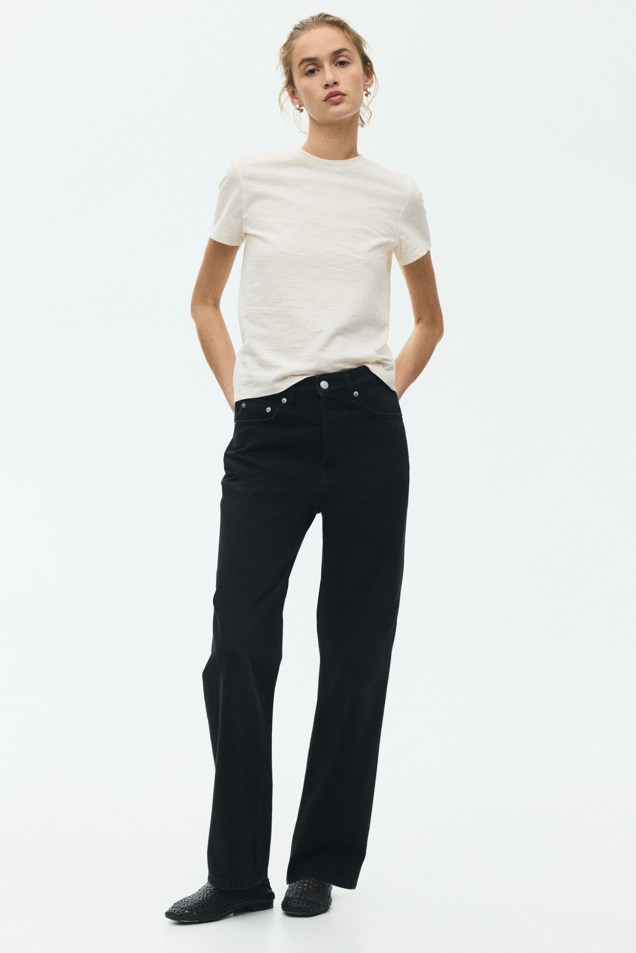 View larger image: Black jeans feature a high-waisted, straight-leg fit, appearing full-length from a front-facing angle. They include a visible button and zipper closure, with front pockets accented by rivets.