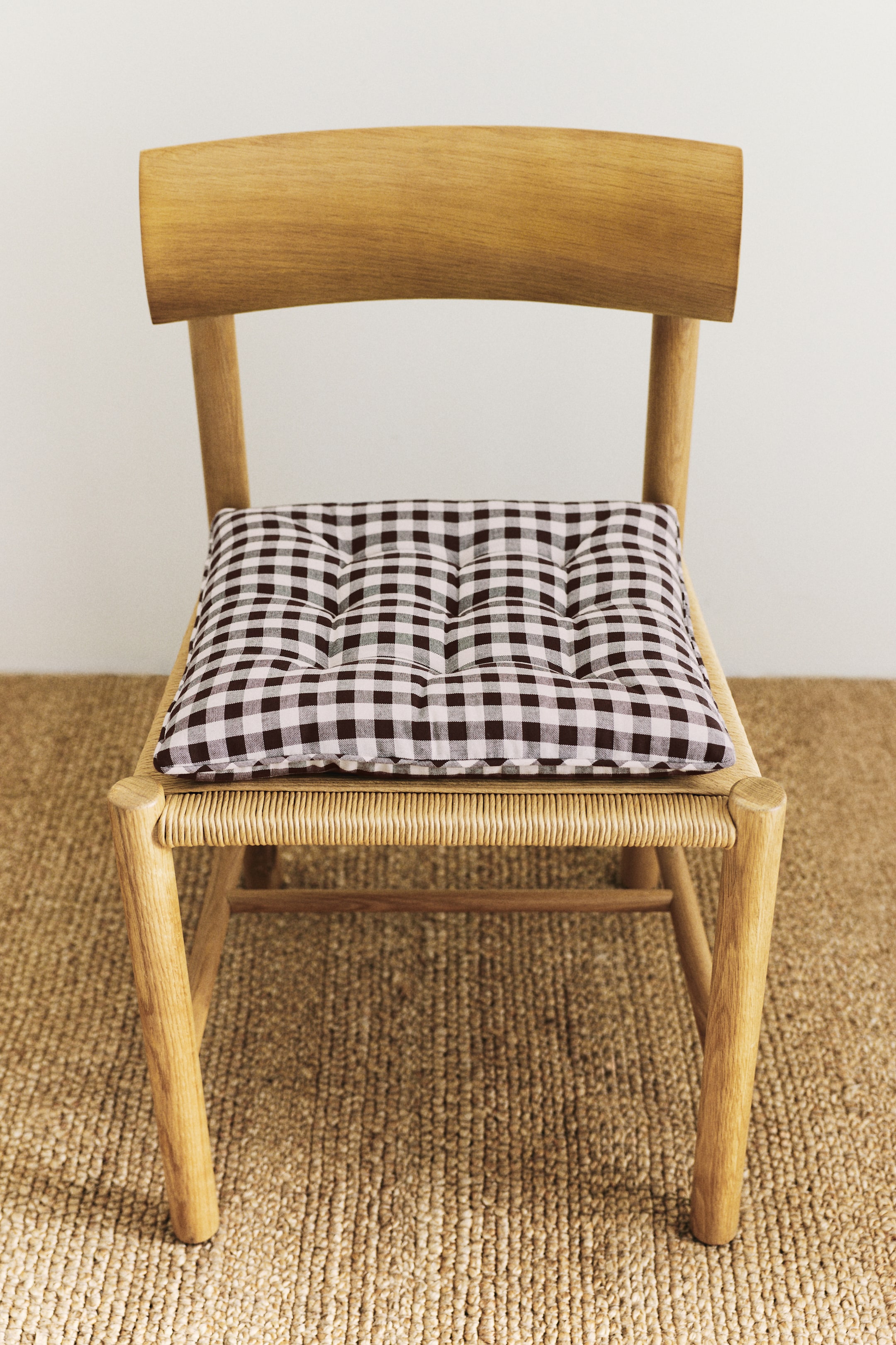 View larger image: The padded seat cushion is showcased FRONT, highlighting a dark brown and white gingham-check pattern on a cotton weave, accented with quilt knots.