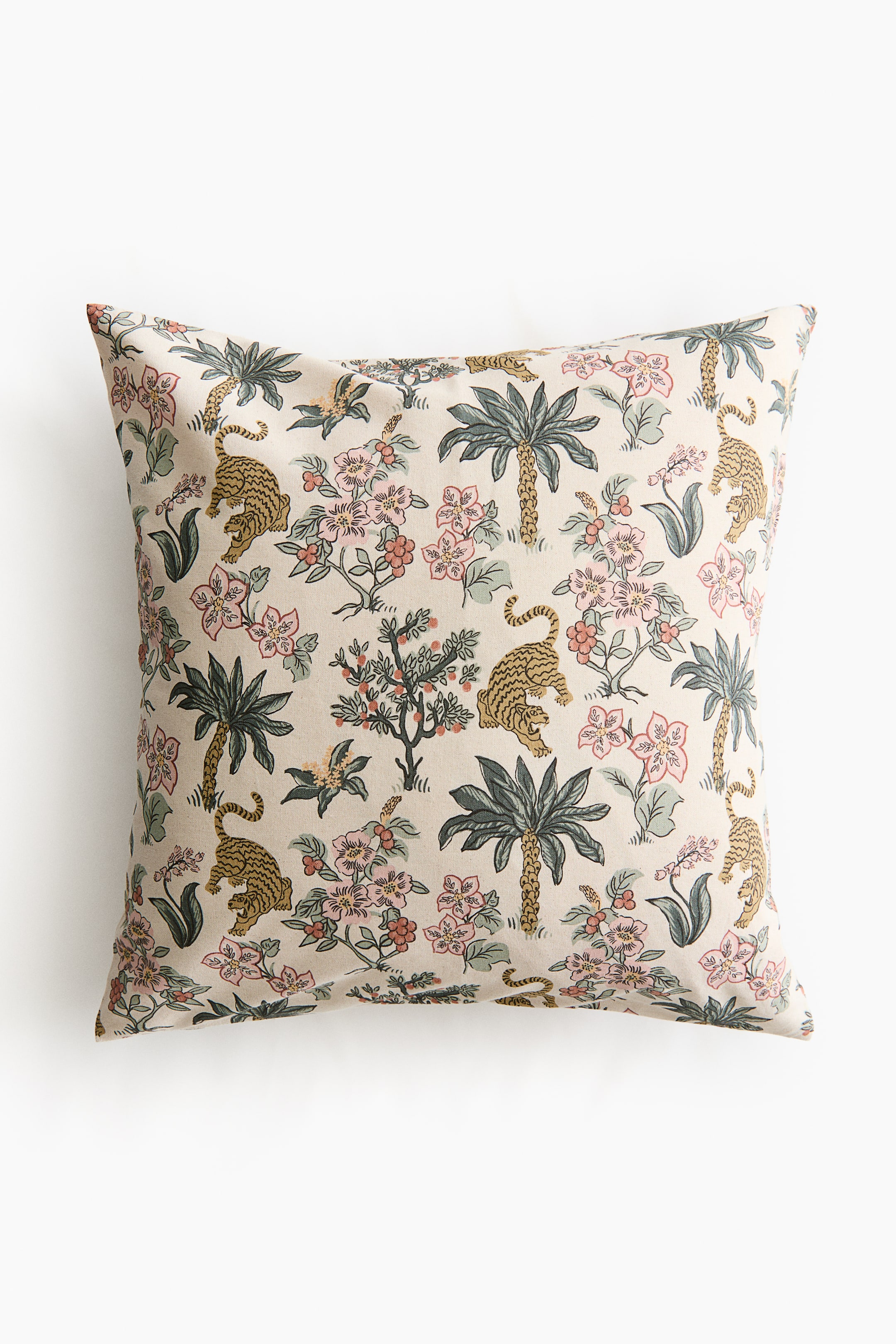 View larger image: A plump, square cotton canvas cushion cover is presenting its front, featuring an all-over printed pattern of tigers, palm trees, and various flowering plants with pink and red blossoms on a light background.