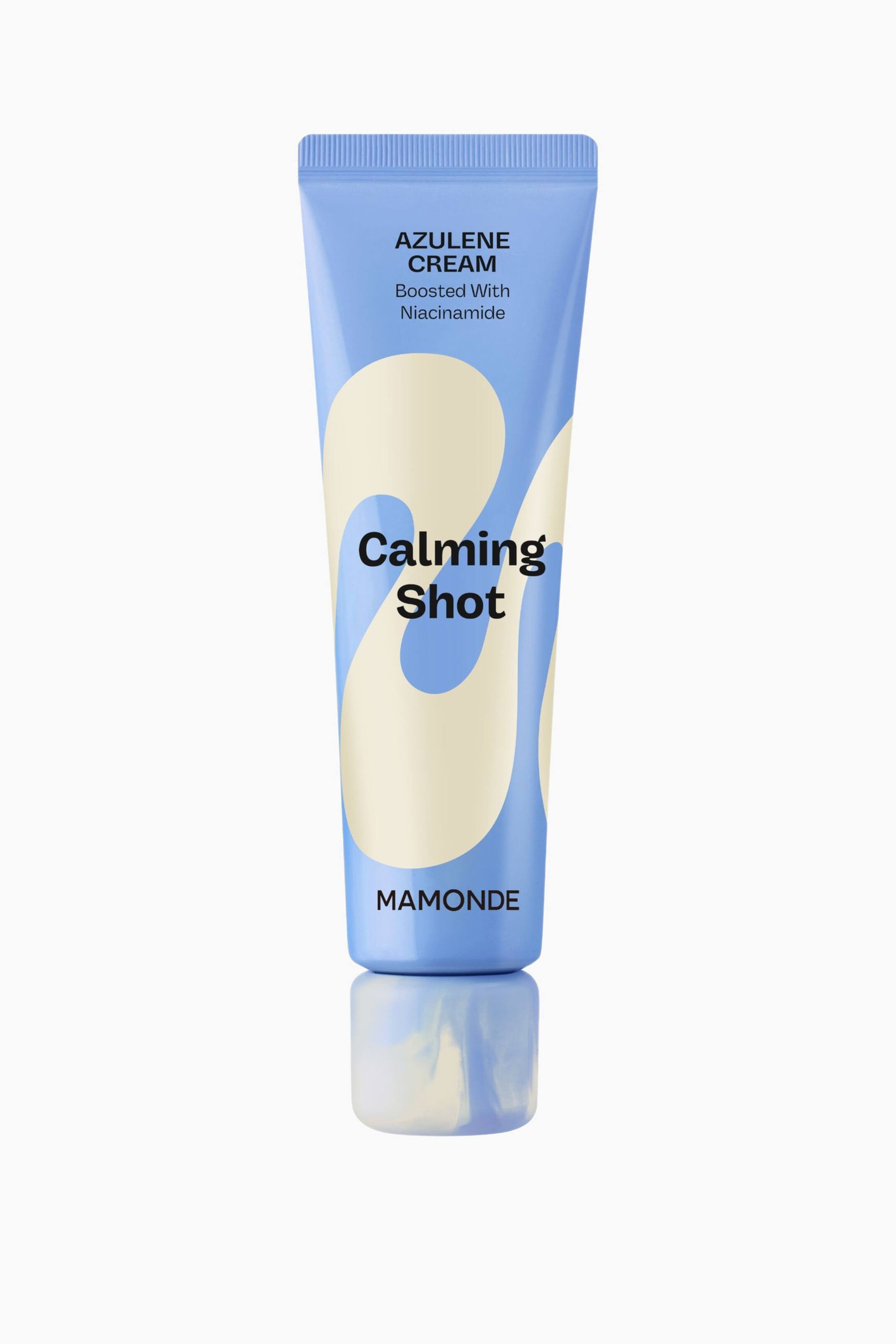 Visa större bild: En ljusblå kosmetisk krämtub står upprätt och har en krusad topp, krämfärgade vågformade mönster samt svart text med orden "AZULENE CREAM", "Boosted With Niacinamide", "Calming Shot" och "MAMONDE."