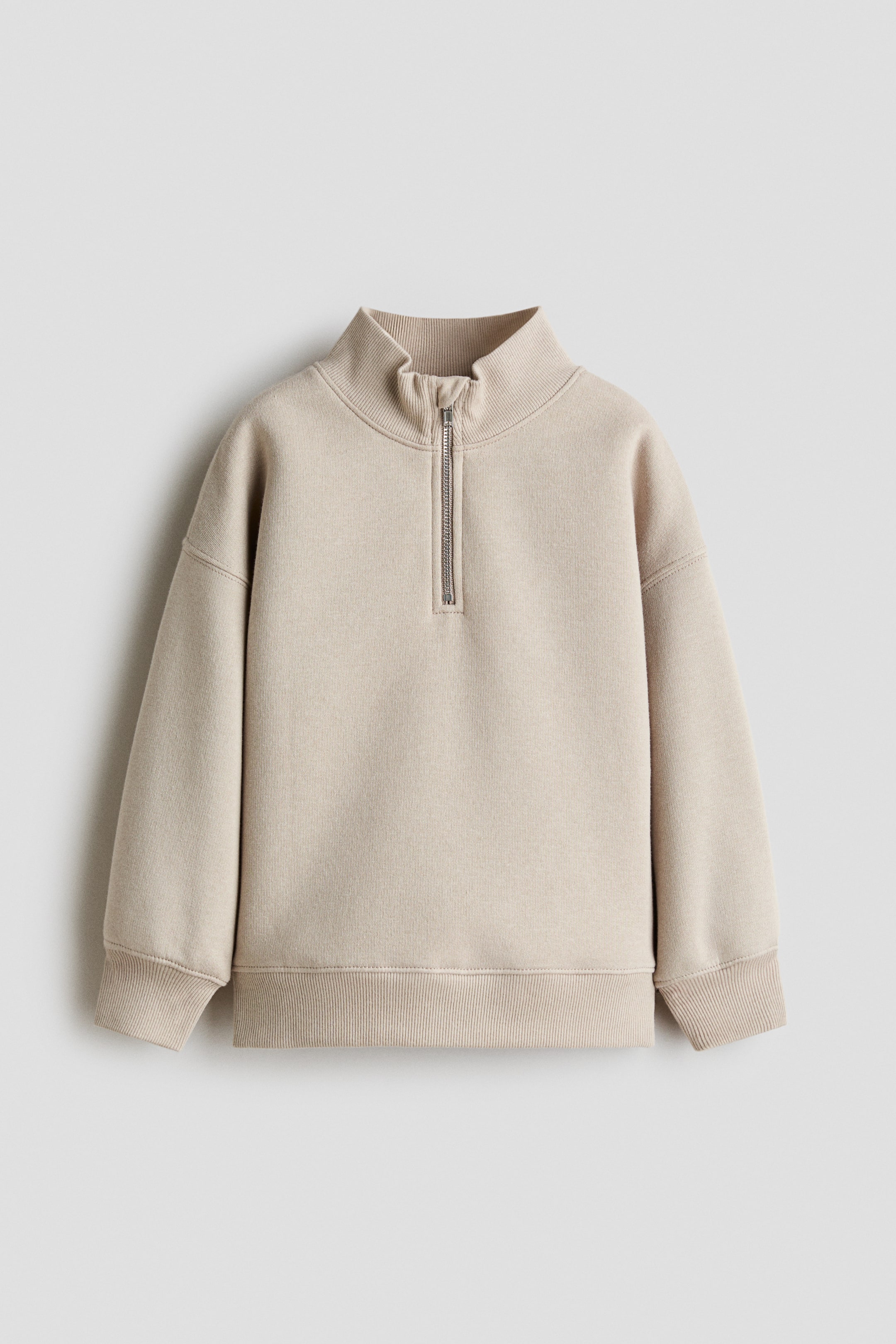 Näytä suurempi kuva: Beige puolivetoketjullinen paita pehmeästä fleece-kankaasta kuvattuna edestä. Siinä on ribattu pystykaulus ja hopeanvärinen metallivetoketju. Mallissa on laskettu olkalinja, pitkät hihat ribatuilla resoreilla sekä yhteensopiva ribattu helma.