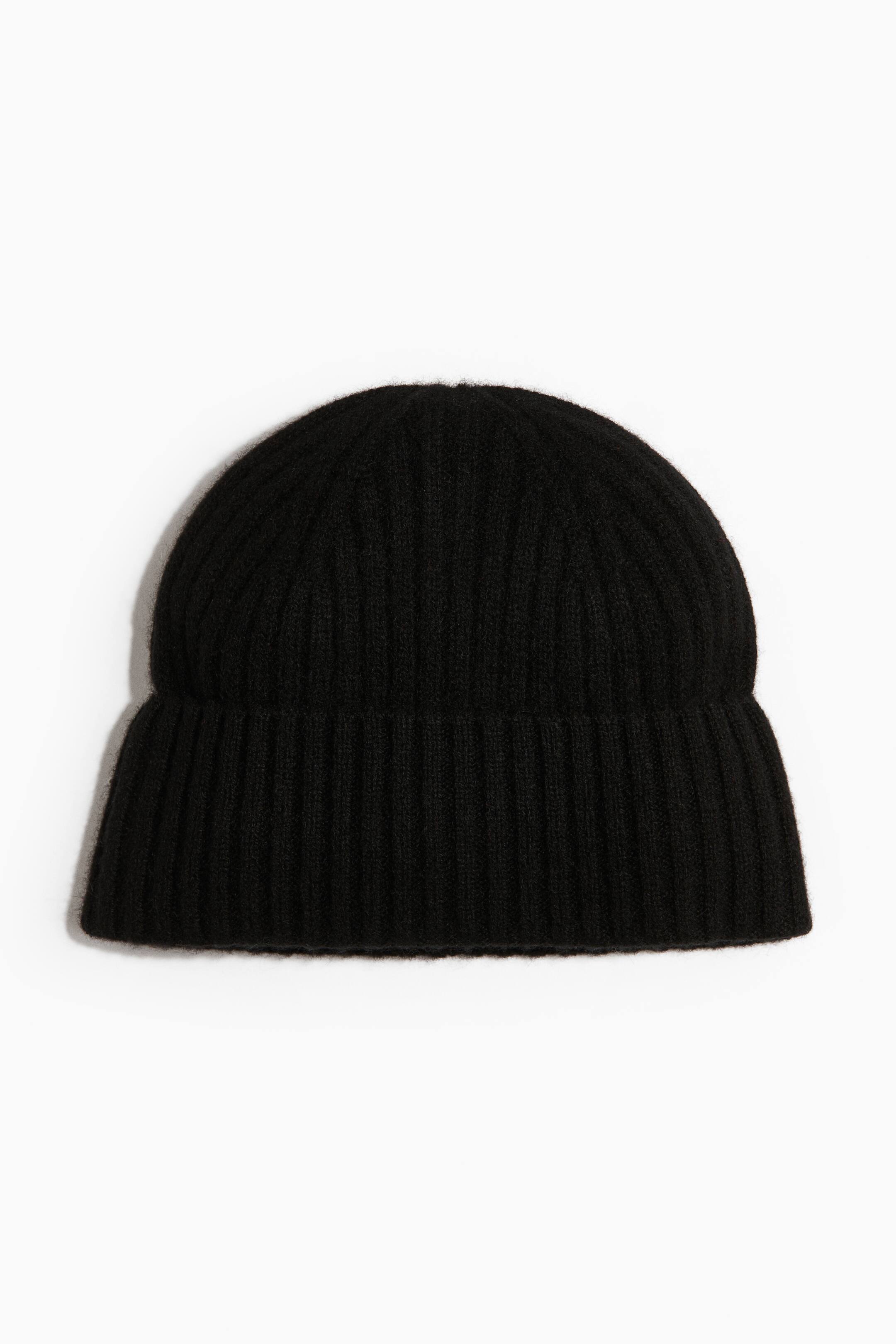 View larger image: A black ribbed knit beanie is shown facing forwards, featuring a rounded crown and a wide, folded cuff. The hat displays a soft, slightly fuzzy texture with vertical ribbed detailing throughout.