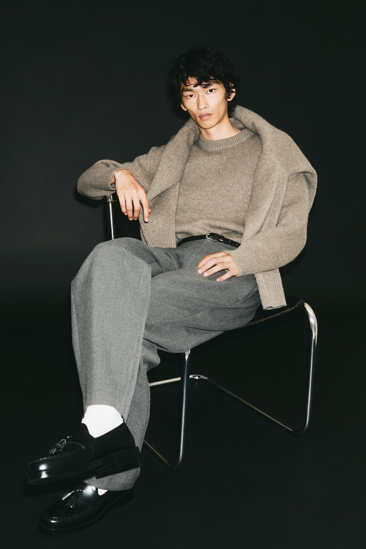 A taupe-brown knitted sweater is shown from the front, showcasing a soft, textured fabric with a classic crew neckline. The design features a thick ribbed collar, dropped shoulders, long sleeves with ribbed cuffs, and a matching ribbed hem. - 1