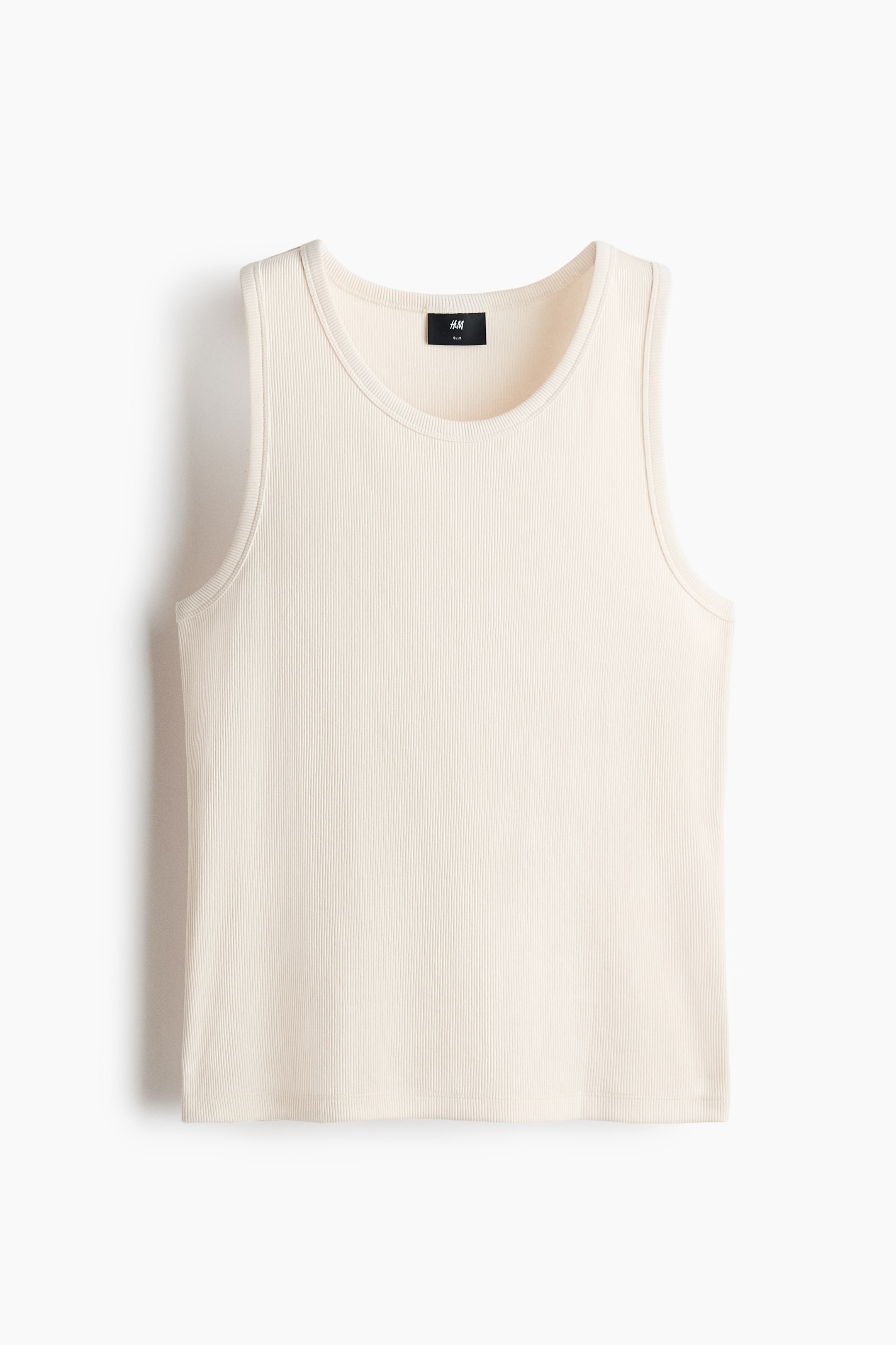 View larger image: A cream ribbed knit tank top is shown from the front, featuring a round neck and sleeveless design. A black H&M label is visible at the back of the neckline.