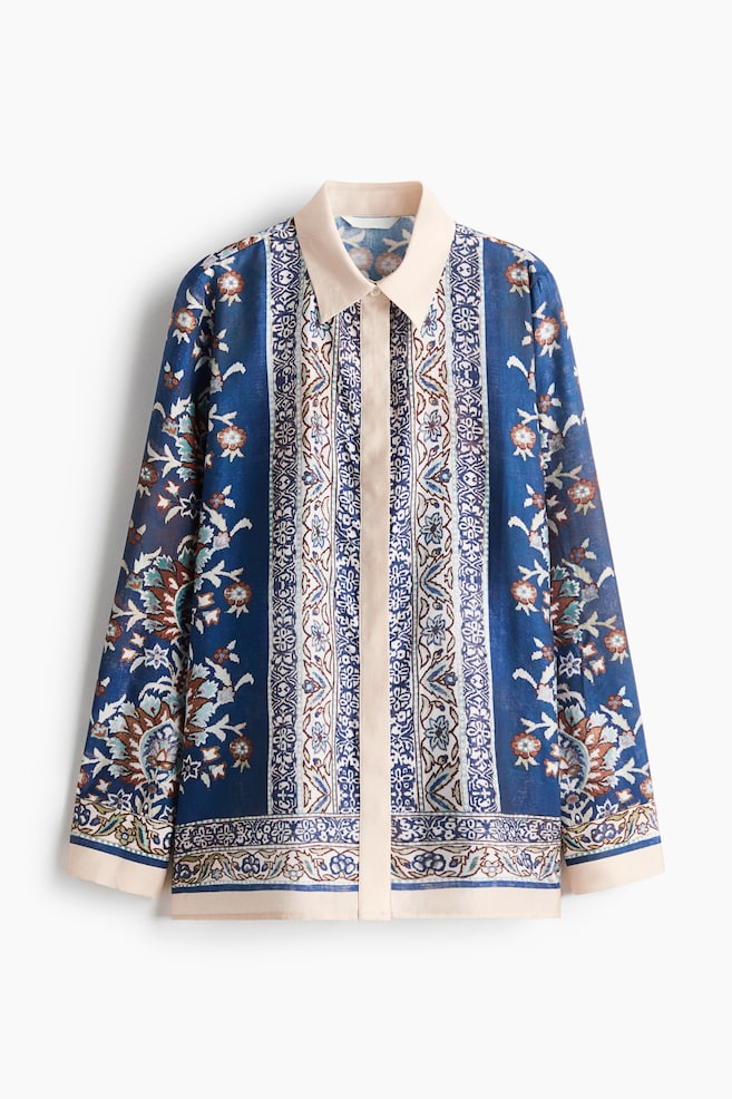 Ein Oversized-Hemd aus einem kunstvoll gemusterten Webstoff aus Viskosemischung in Blau und Creme hängt frontseitig und verfügt über einen kontrastierenden cremefarbenen Kragen, eine verdeckte Knopfleiste, lange Ãrmel mit cremefarbenen Manschetten sowie einen gerade geschnittenen Saum. - 1