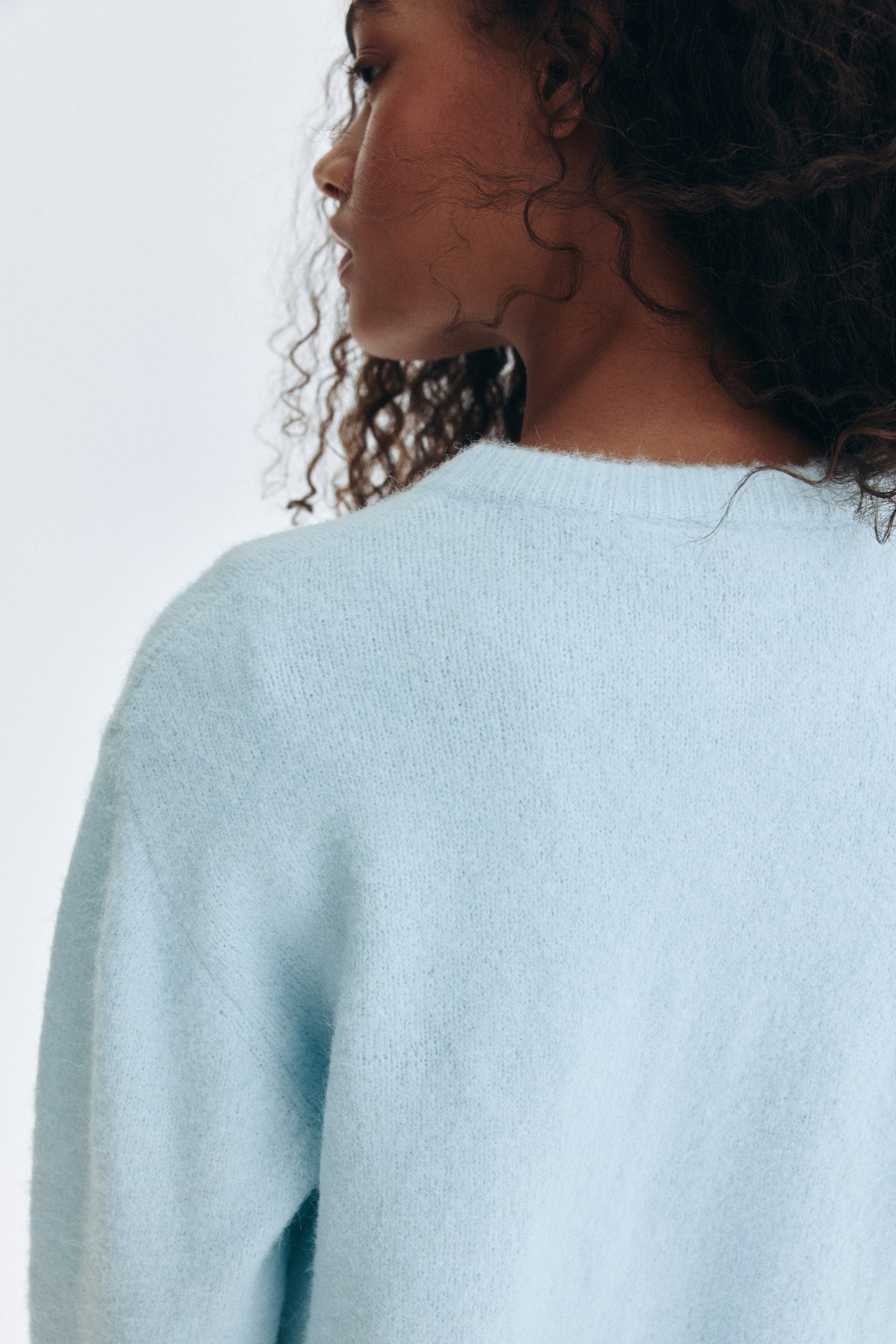 Visualizza immagine più grande: La modella indossa un maglione a girocollo blu chiaro in maglia morbida.