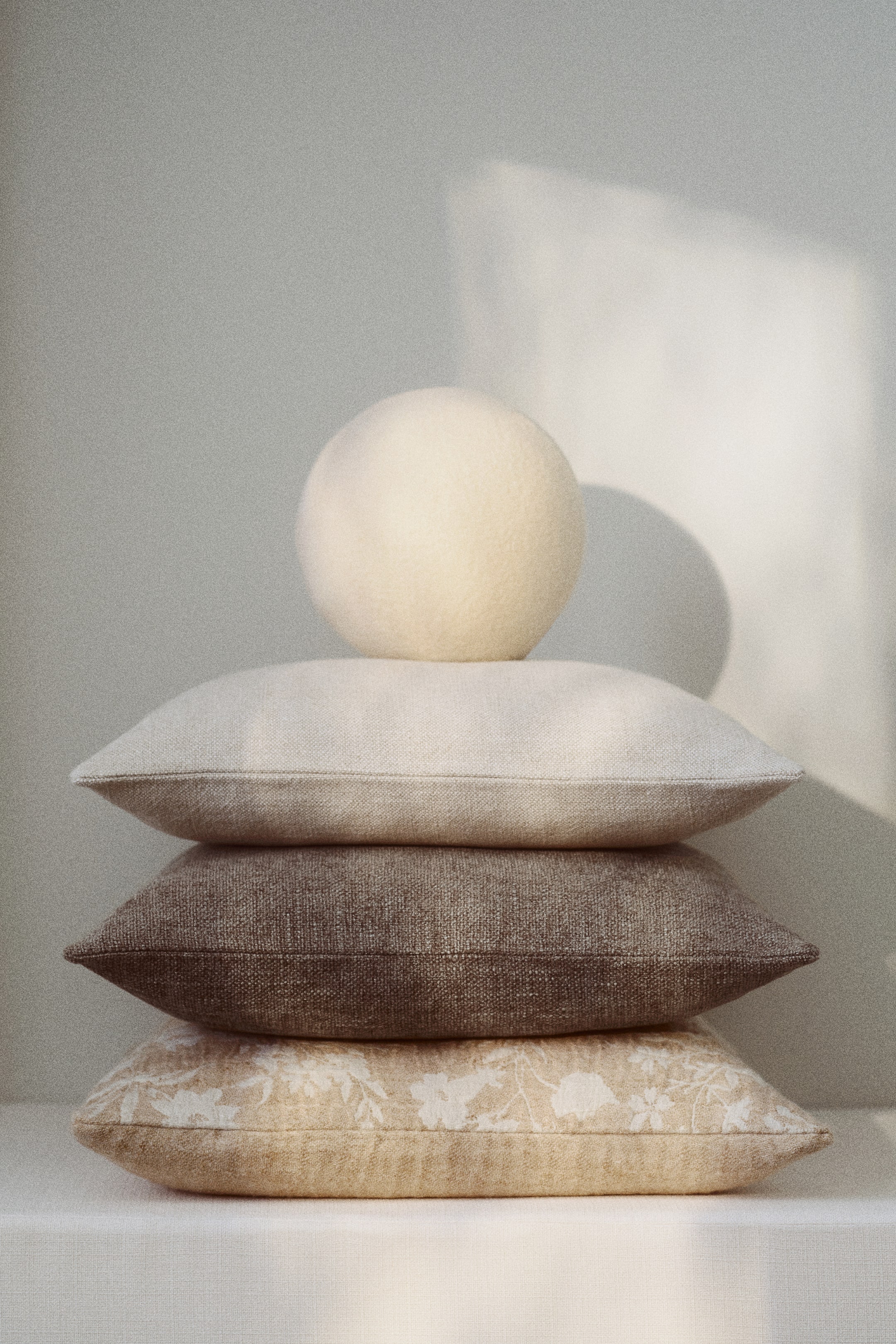 Voir une image plus grande: Une housse de coussin beige clair se présente de face, mettant en valeur un tissage texturé en mélange de lin, et est empilée dans une pile de housses de coussin.