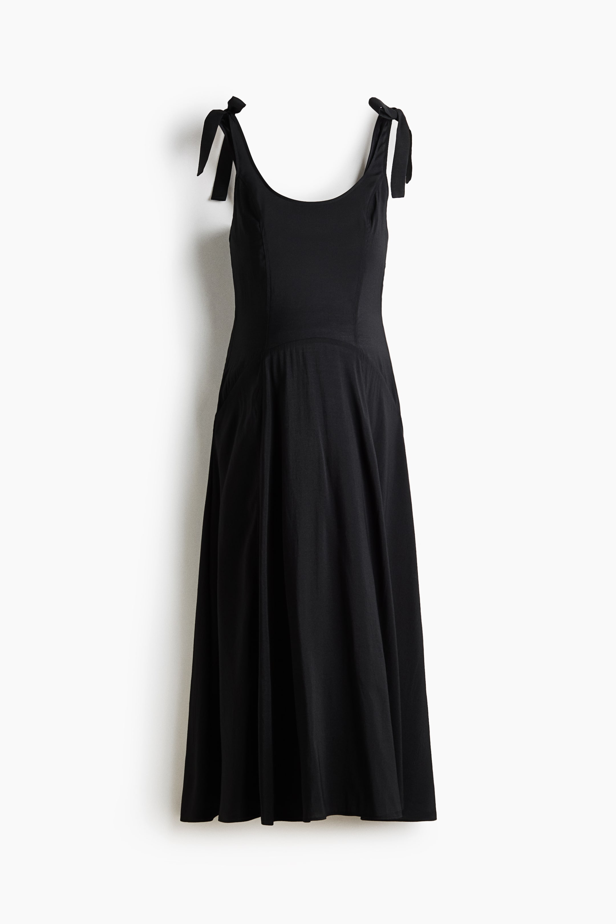 Agrandir l'image: Une robe noire présente un décolleté en forme de cuillère et des bretelles nouées en nœuds. Un corsage ajusté se transforme en une jupe évasée en ligne A, s'étendant jusqu'à une longueur midi.