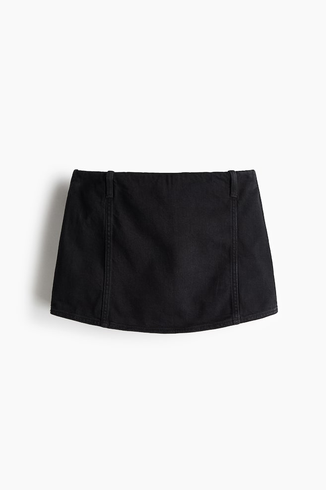Se presenta de FRENTE una minifalda de mezclilla negra, con pretina plana, dos pequeñas trabillas en la parte superior y costuras verticales en el panel frontal. El dobladillo inferior es sutilmente curvo. - 1