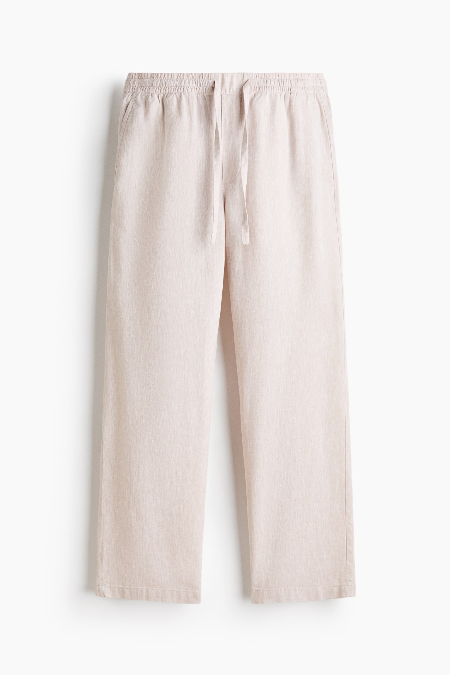 These light beige trousers are hanging in a front view, showcasing a relaxed, straight-leg cut made from textured, linen-like fabric. The design features an elasticised waistband with an adjustable drawstring and discreet side seam pockets.