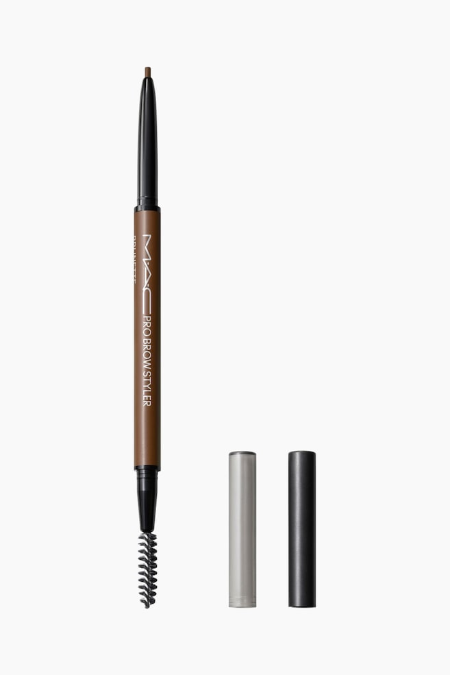 Pro Brow Styler Fill & Shade Brow Pencil stÃ¥r lodret og fremviser et dobbelt-ende design med en synlig fin, brun blyantspids Ã¸verst og en sort spoolie-bÃ¸rste nederst. Den brune midterste barrel viser hvid branding, mens to separate cylindriske hÃ¦tter i sÃ¸lv og mat sort stÃ¥r oprejst ved siden af. - 1