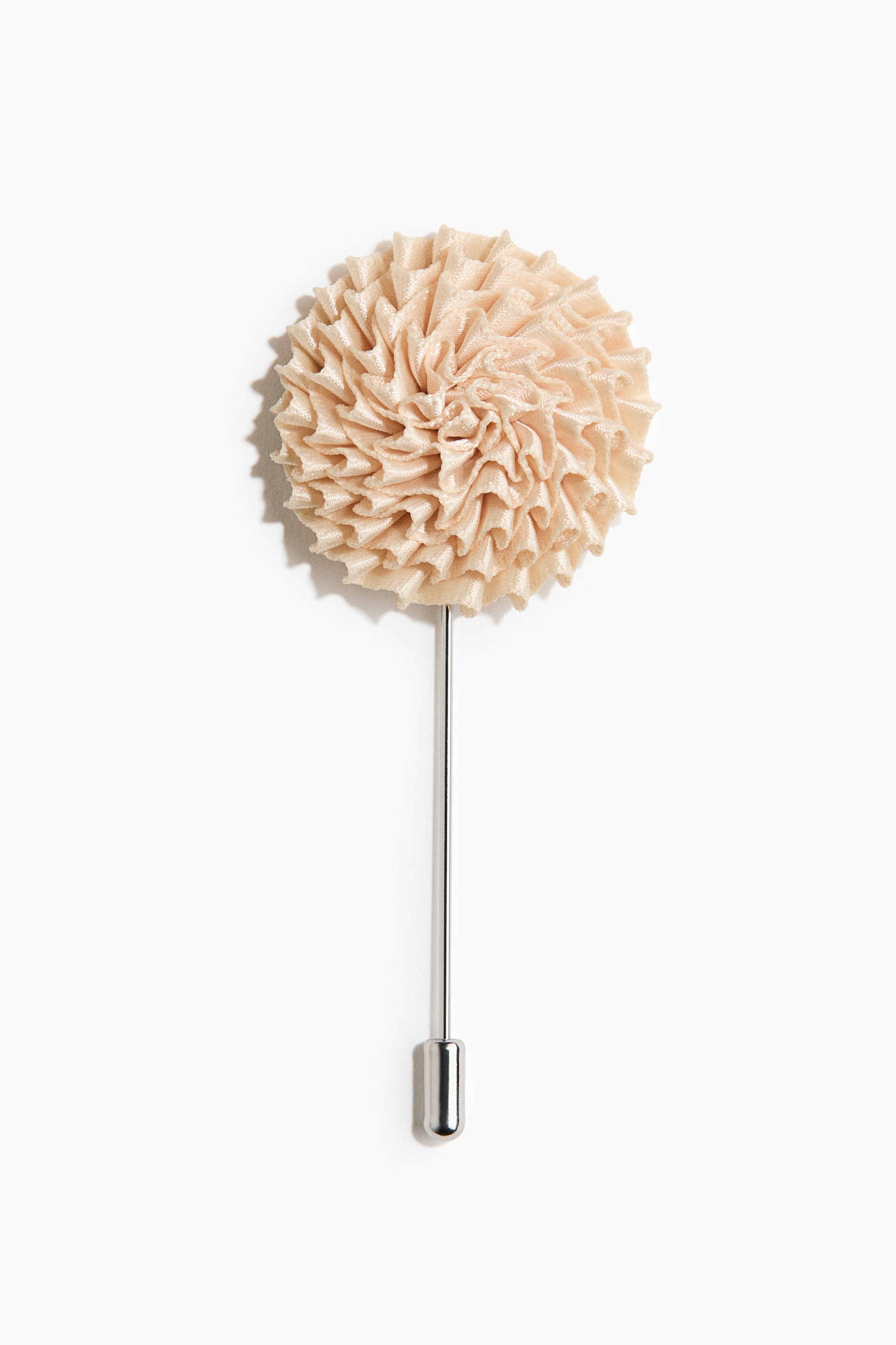 Agrandir l'image: Une épinglette présente une rosette en tissu beige clair circulaire et plissée, fixée à une épingle fine de couleur argentée avec un capuchon assorti.