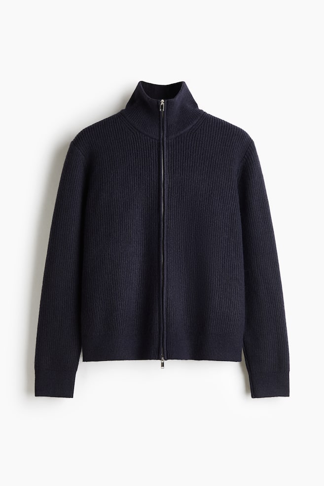 A navy blue rib-knit cardigan is displayed from the front, featuring a high stand collar, a two-way front zip fastening, and long sleeves. The garment showcases a regular-fit silhouette with a consistent vertical ribbed texture. - 1