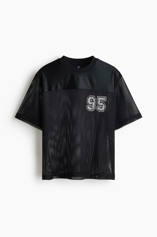 A black mesh t-shirt is featuring a round rib-trimmed neckline, dropped shoulders, and a solid black yoke across the top front. It is displaying a sparkling white "95" graphic on the mesh body, presenting a straight-cut hem and a loose fit. - 1